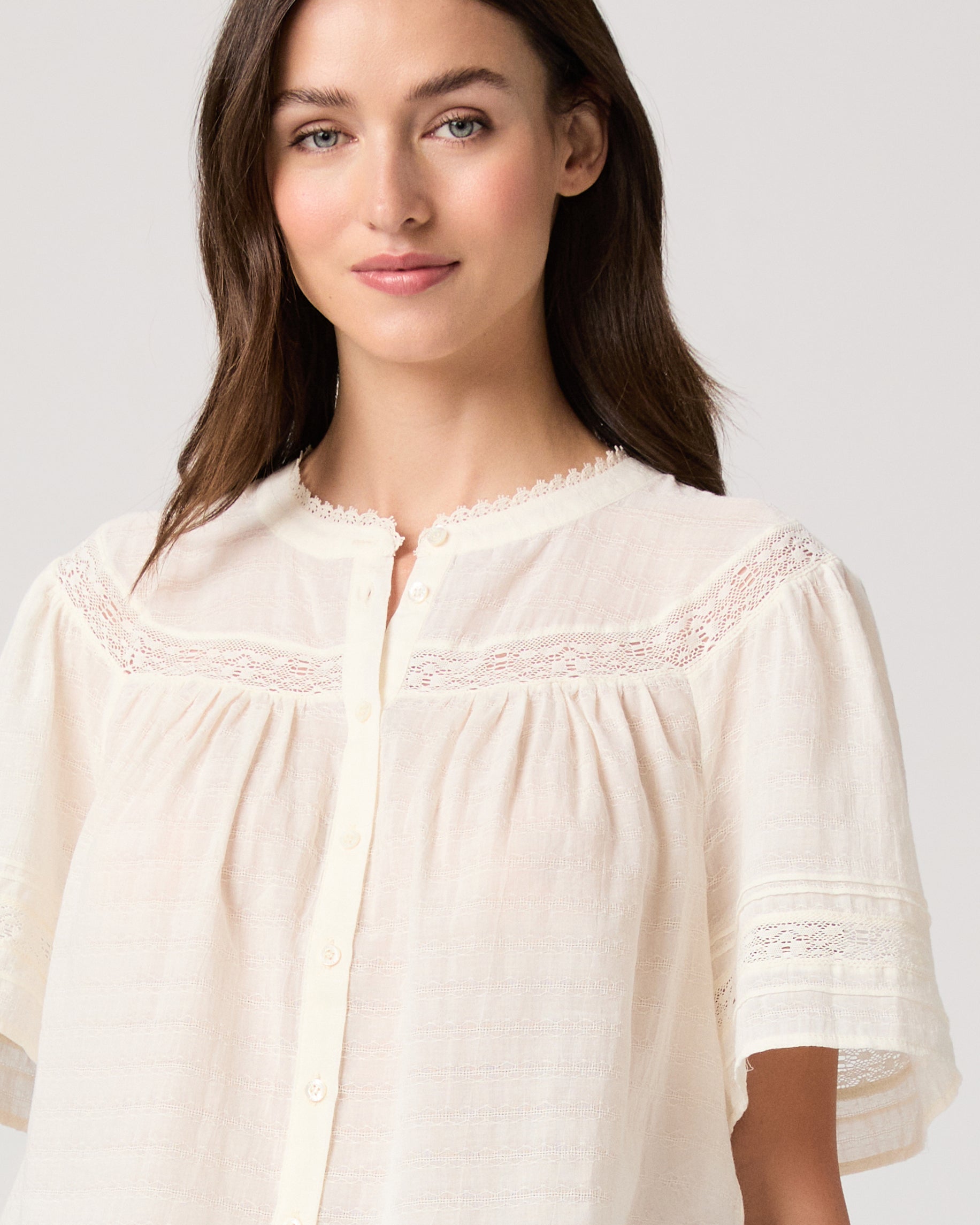 Pasadena Blouse - Ivory Model wearing a white top paired with light green pants with brown sandals