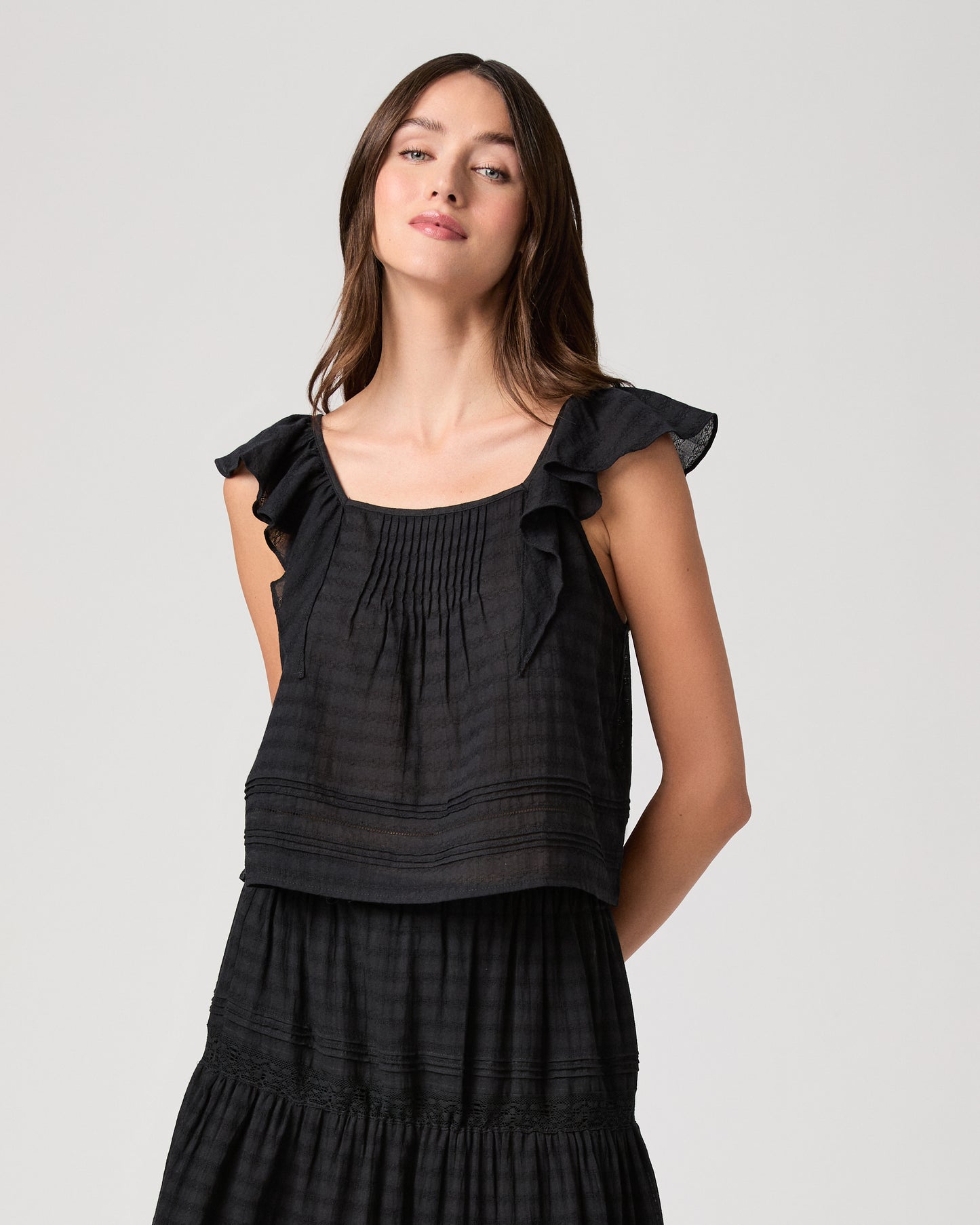 Model wearing a black midi skirt paired with a black  top and gold sandals