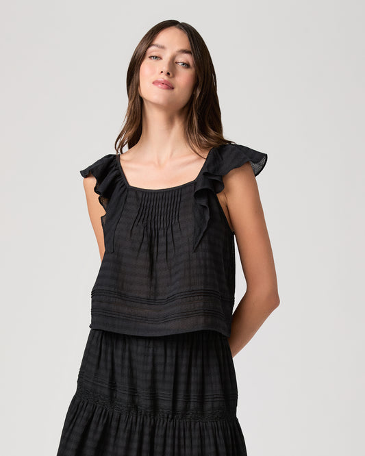 Model wearing a black midi skirt paired with a black  top and gold sandals