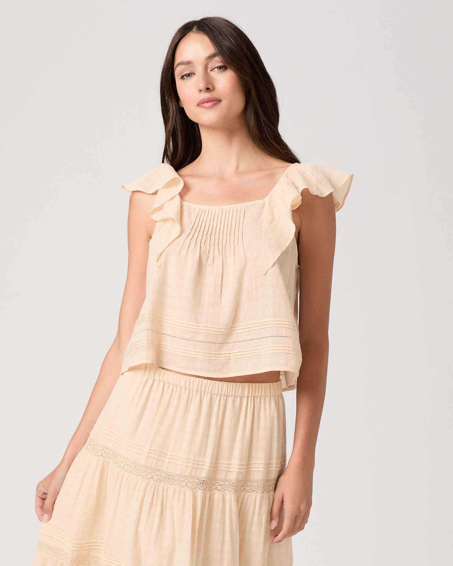 Model wearing a light peach midi skirt paired with a light peach top and brown sandals