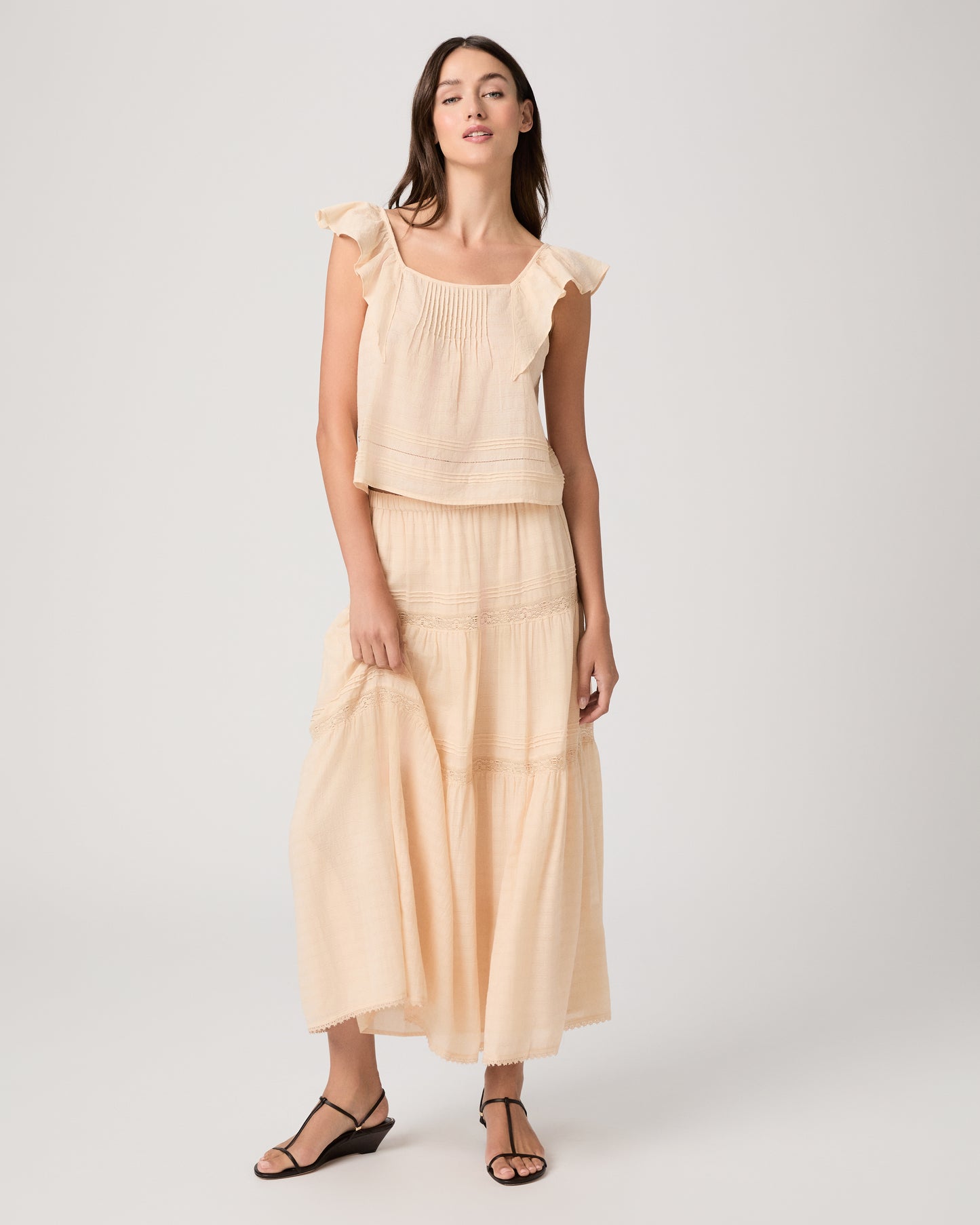 Model wearing a light peach midi skirt paired with a light peach top and brown sandals