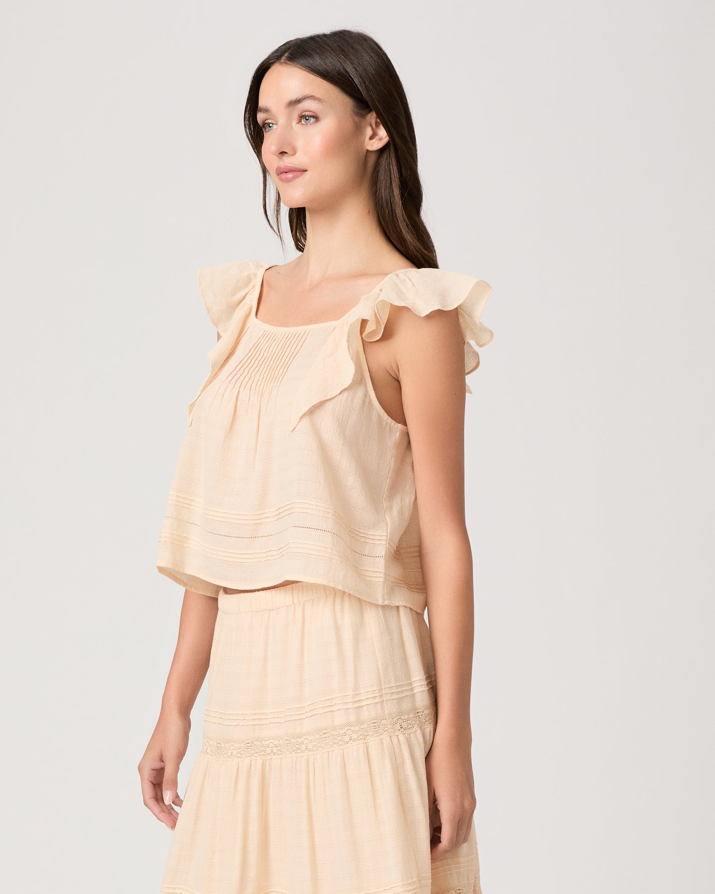 Model wearing a light peach midi skirt paired with a light peach top and brown sandals