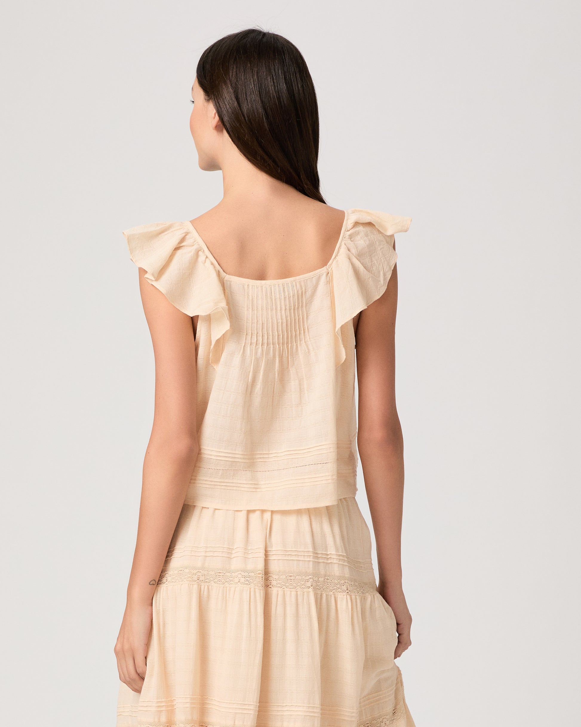 Model wearing a light peach midi skirt paired with a light peach top and brown sandals