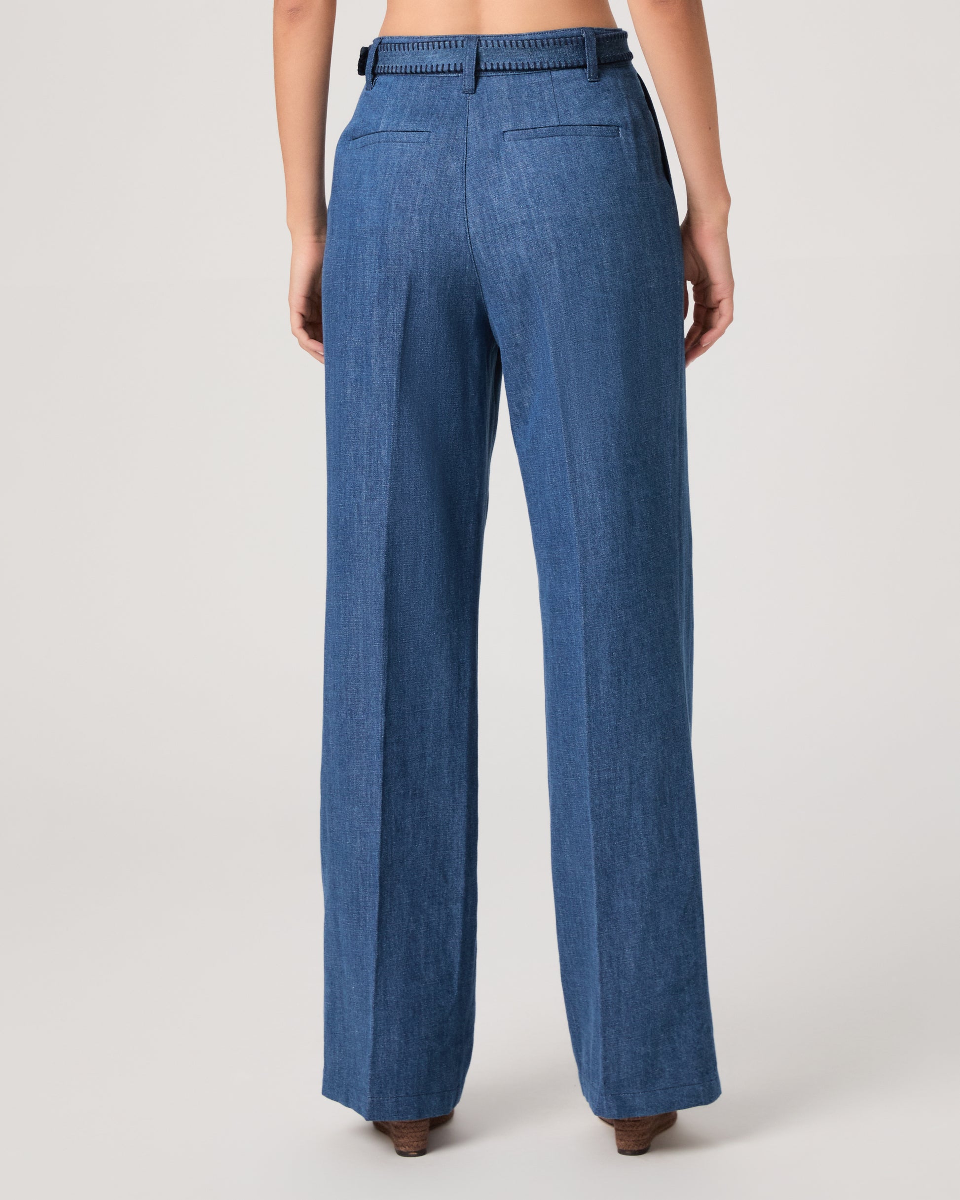 Woman wearing a denim top paired with matching denim pants on a white background