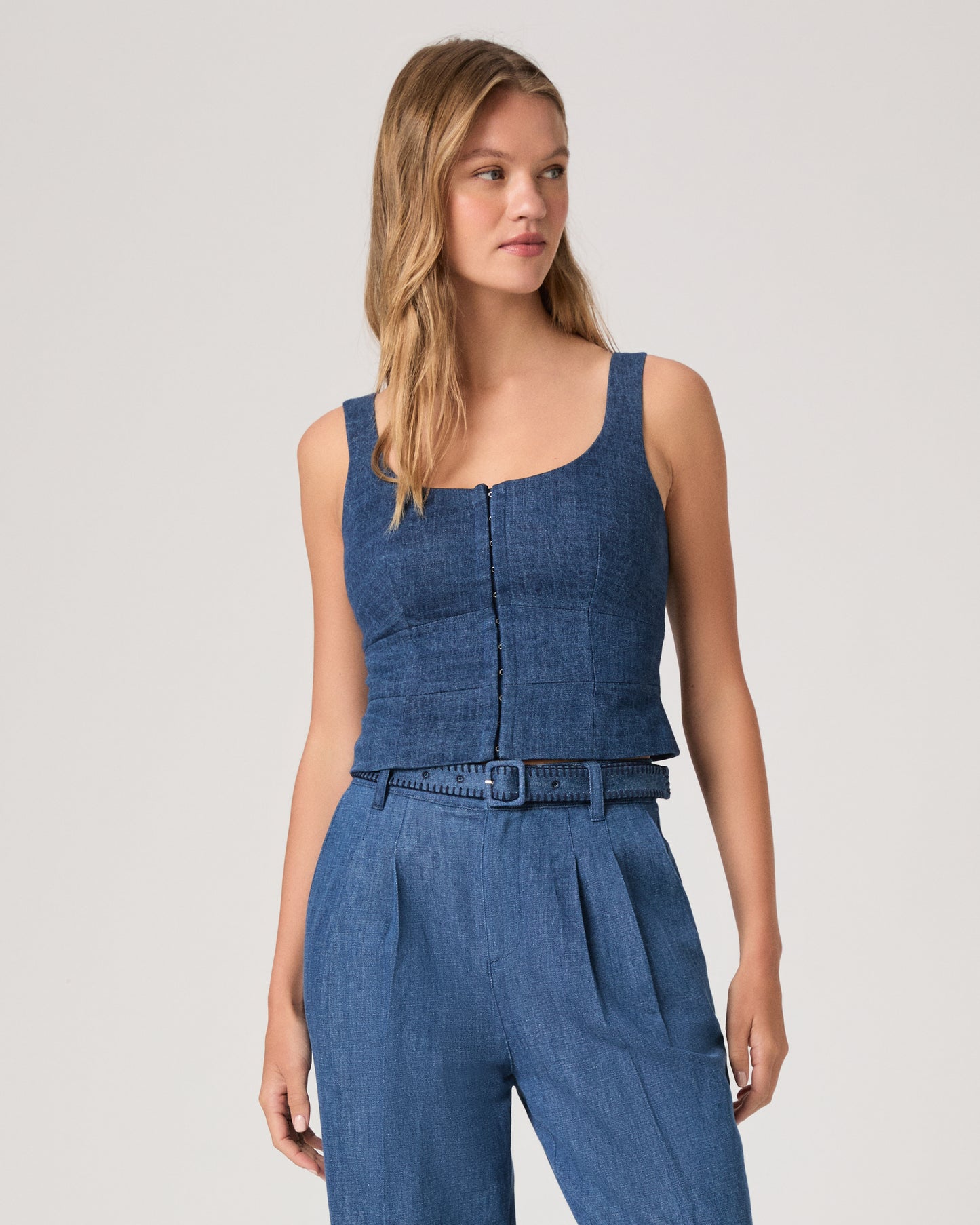 Woman wearing a denim top paired with matching denim pants on a white background