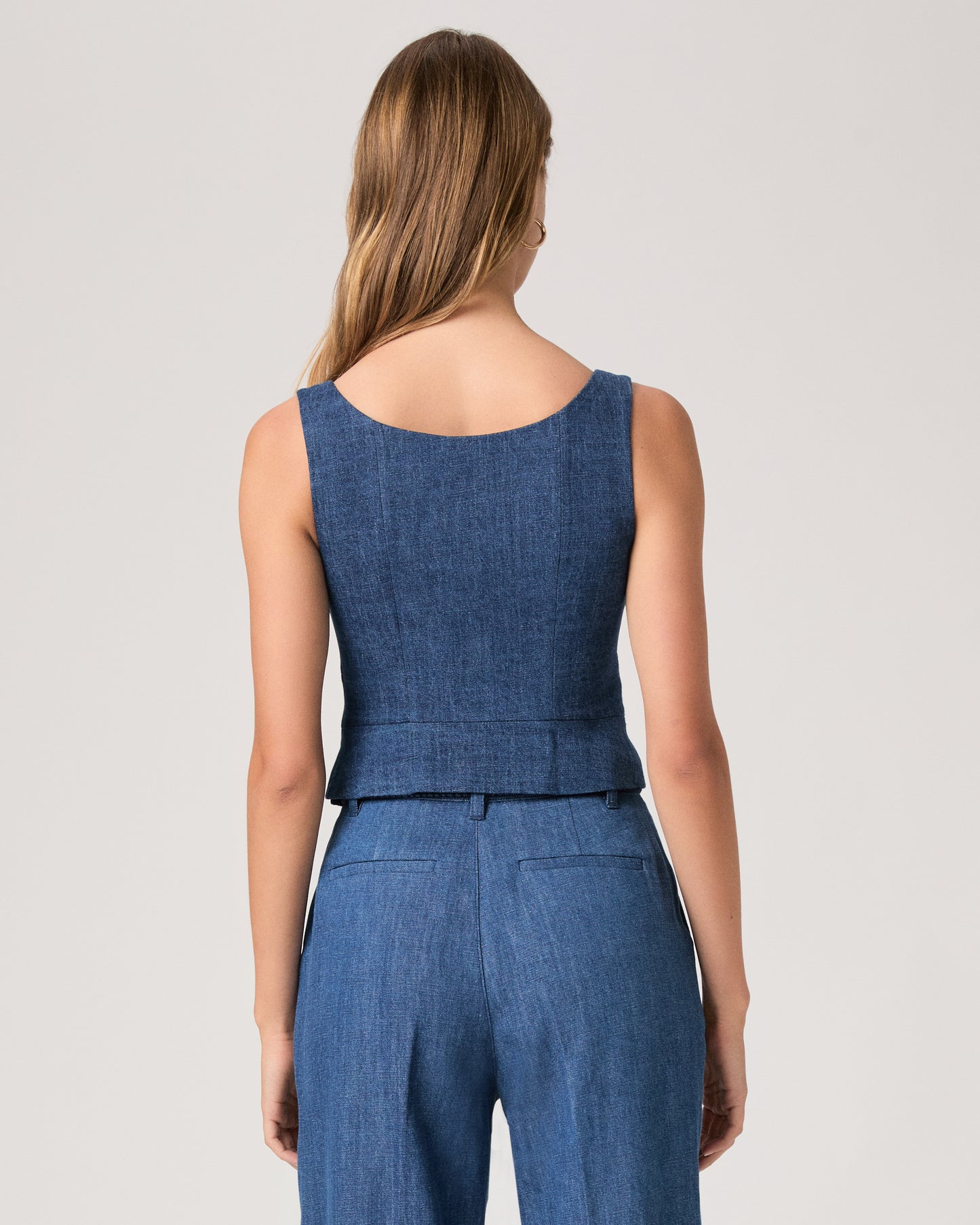 Woman wearing a denim top paired with matching denim pants on a white background