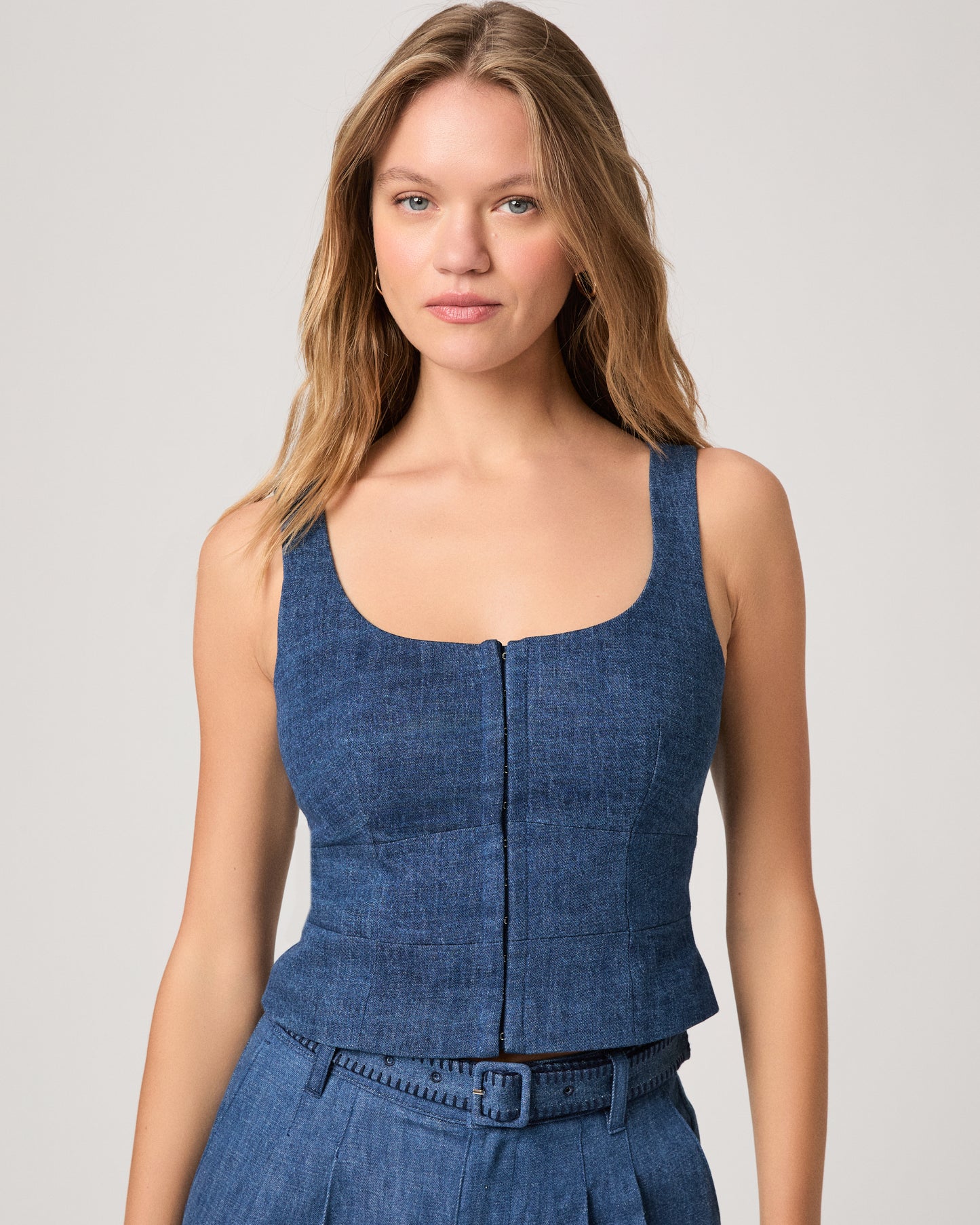 Woman wearing a denim top paired with matching denim pants on a white background