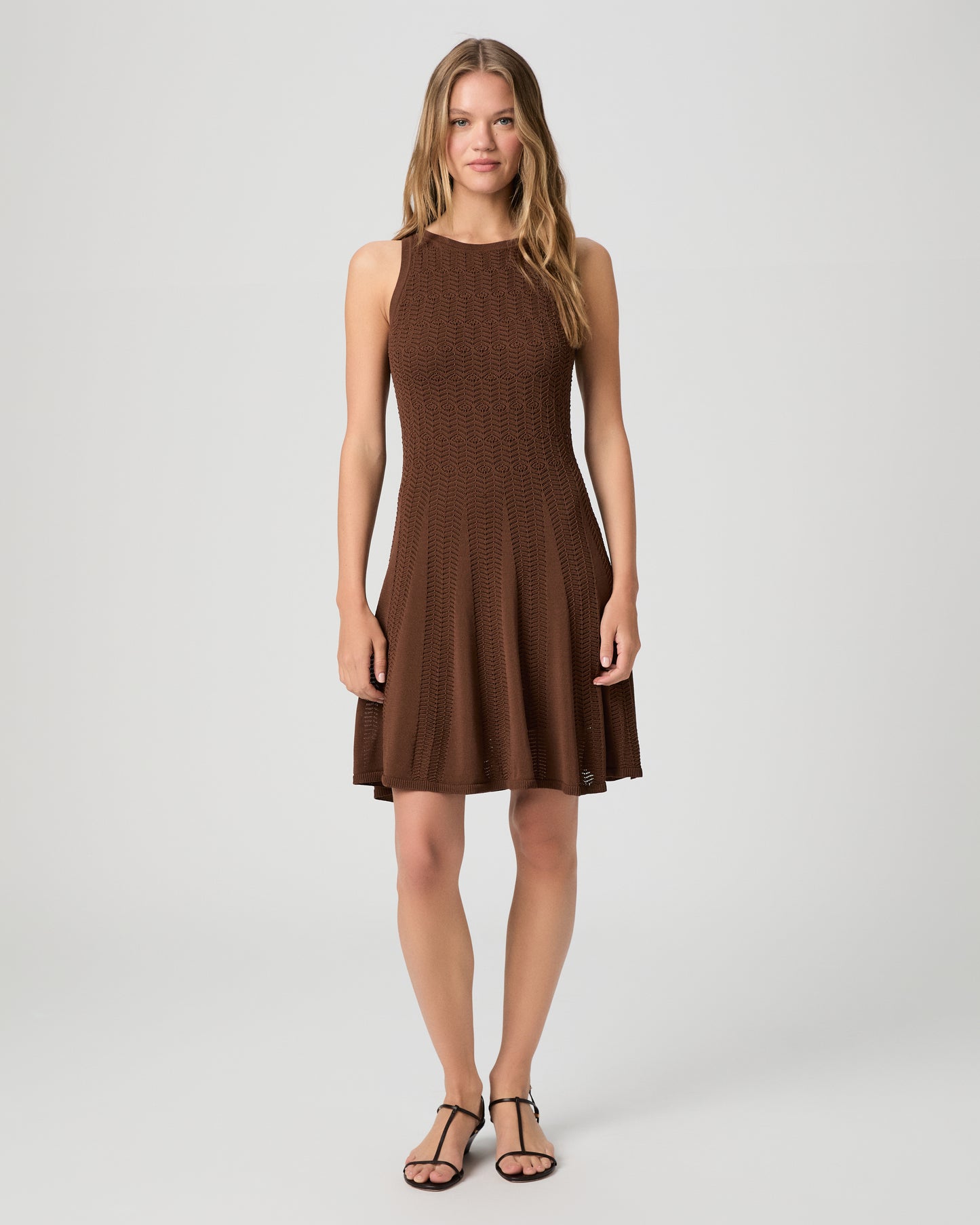 Woman wearing a brown dress paired with brown sandals on a white background