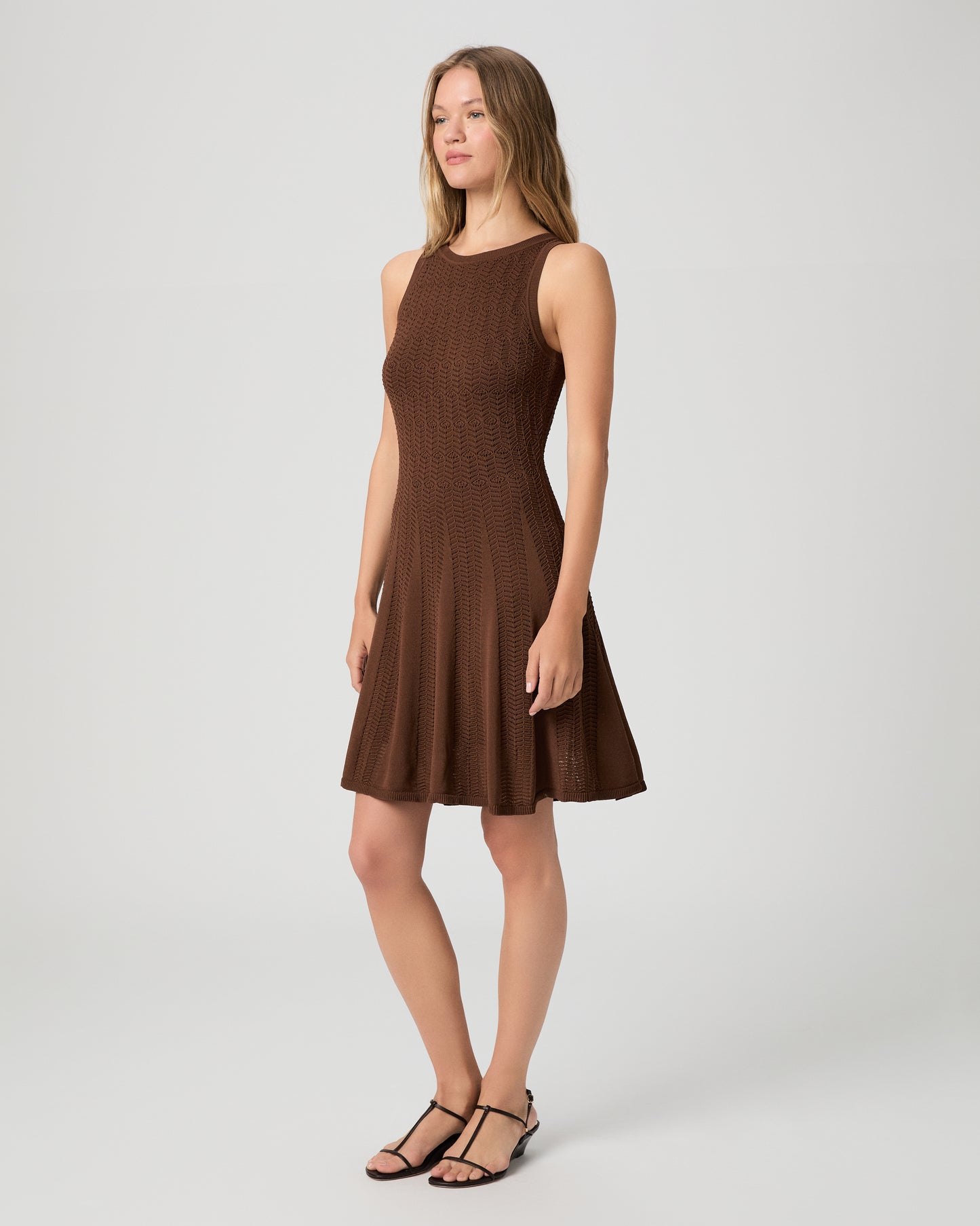 Woman wearing a brown dress paired with brown sandals on a white background