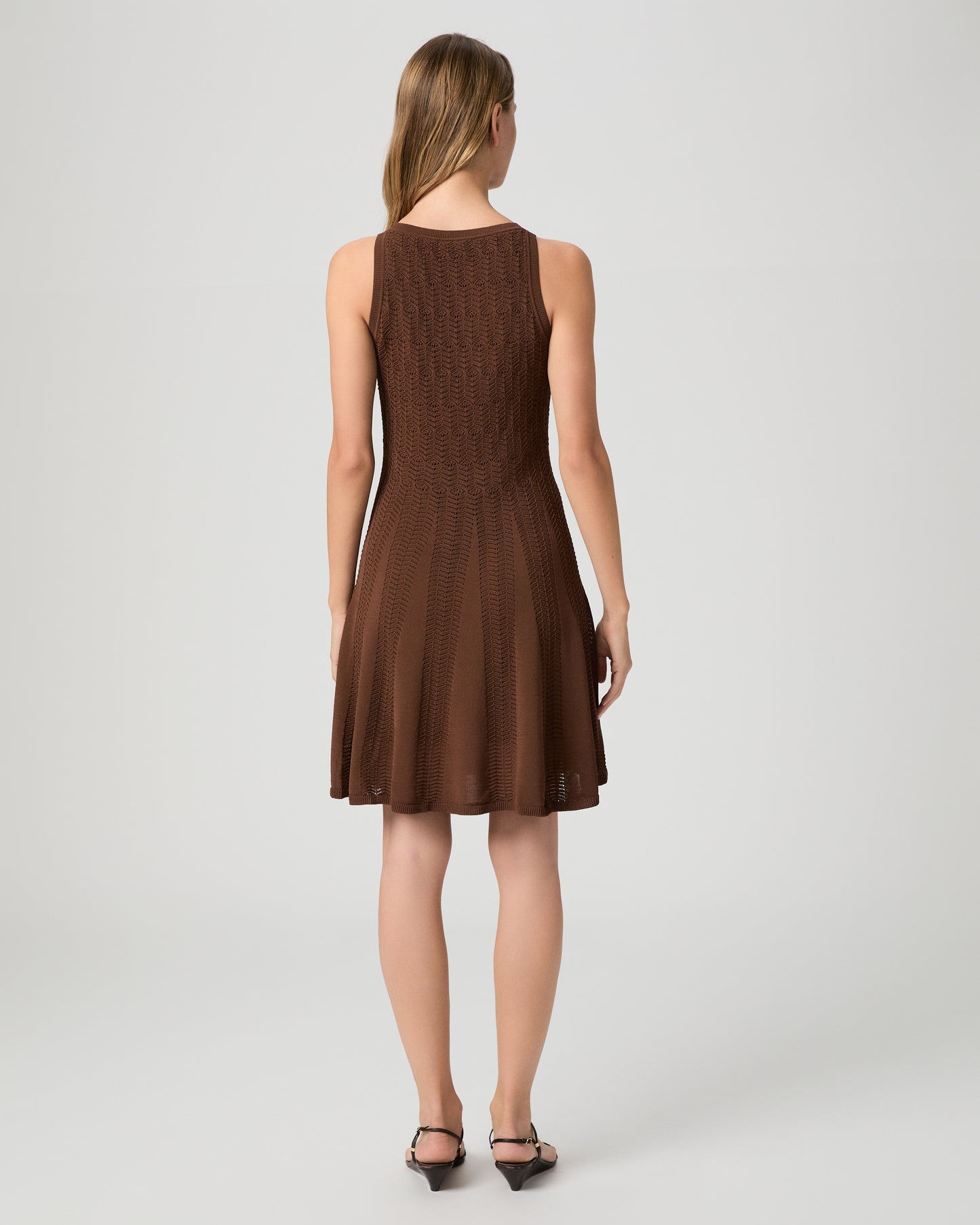 Woman wearing a brown dress paired with brown sandals on a white background