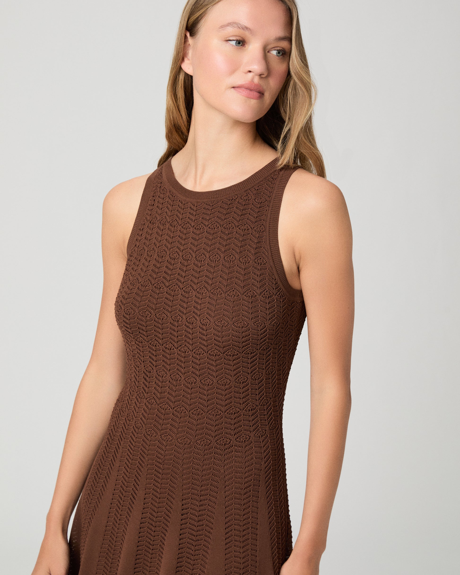 Woman wearing a brown dress paired with brown sandals on a white background