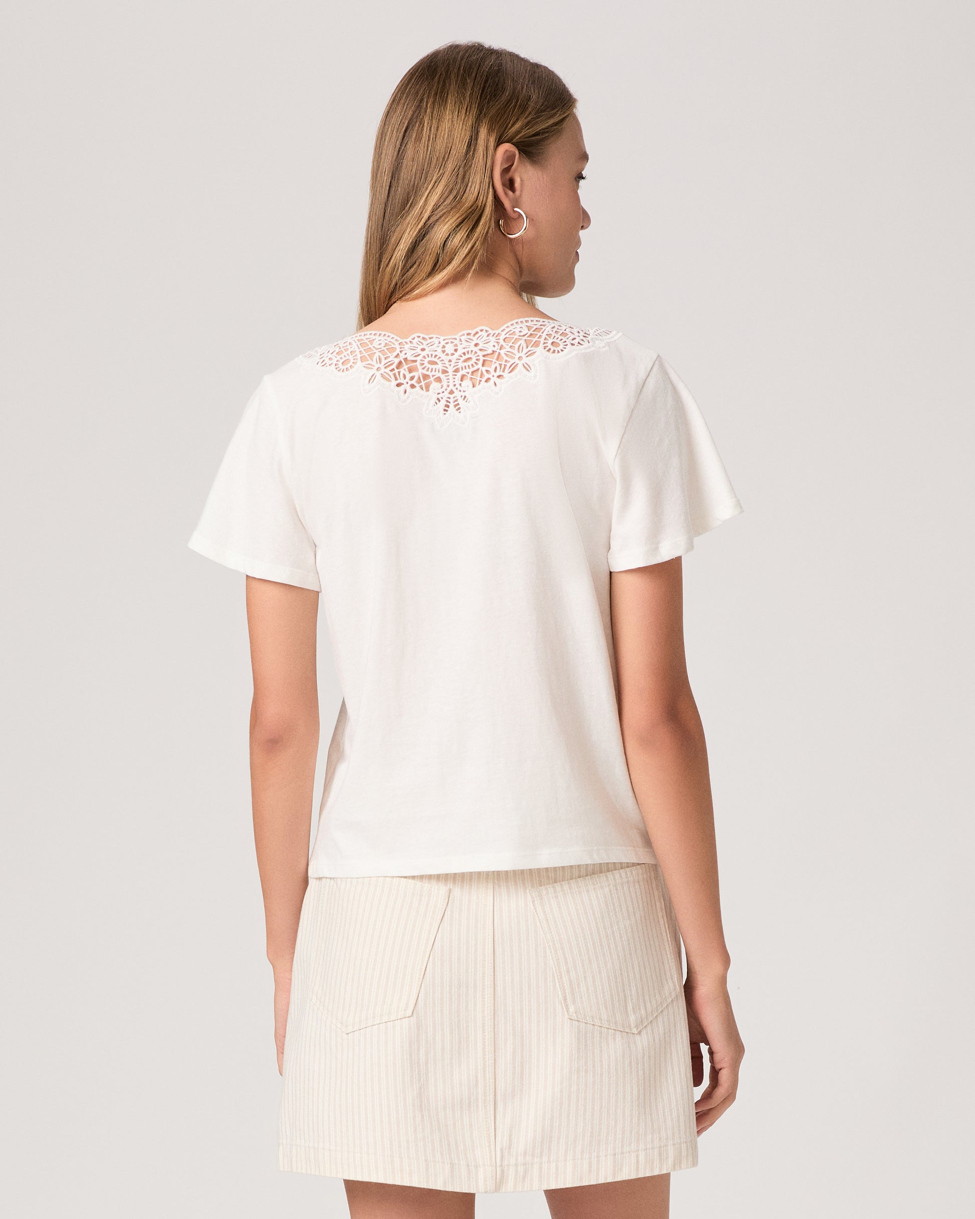 Woman wearing a white top paired with off white skirt on a white background