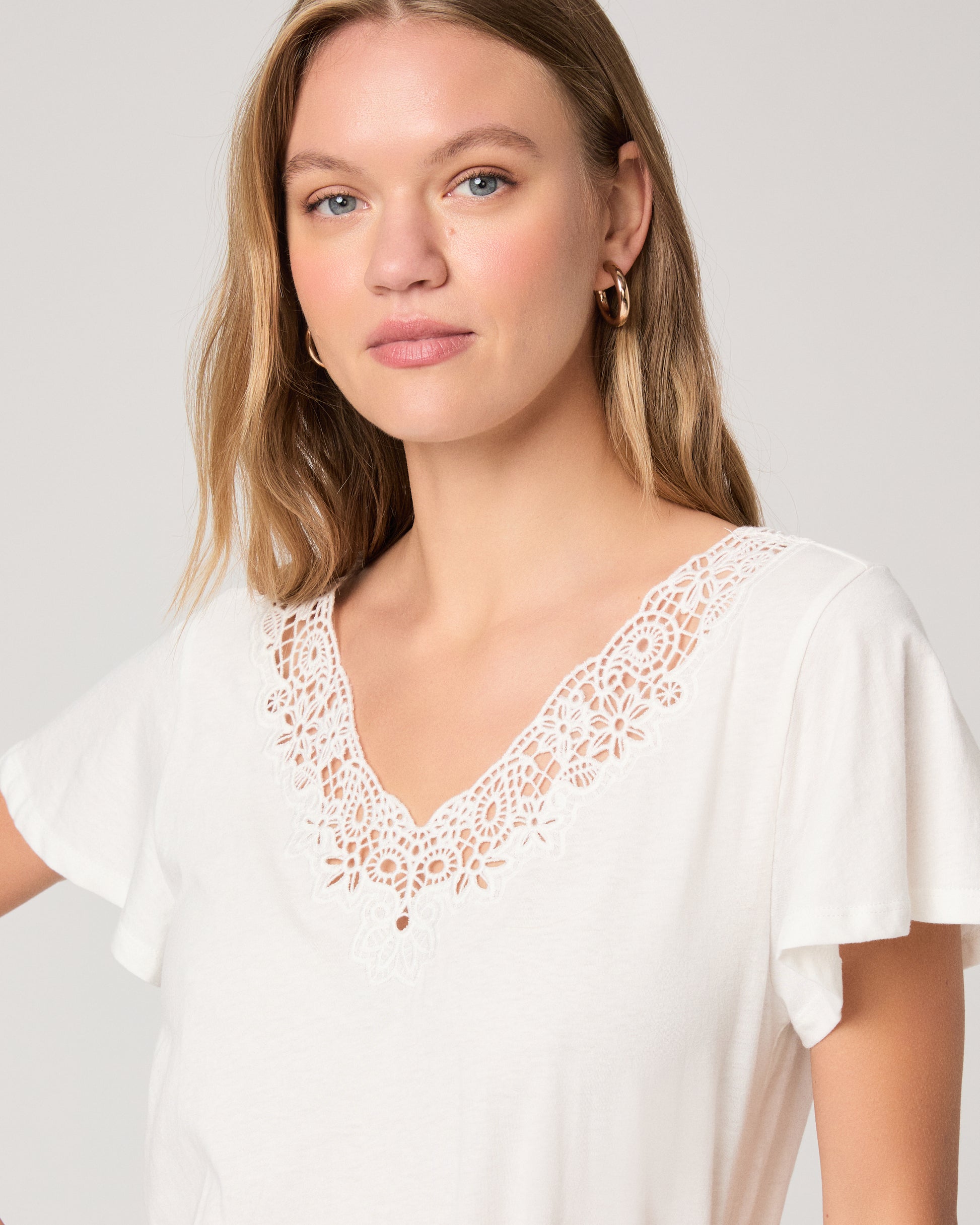 Woman wearing a white top paired with off white skirt on a white background