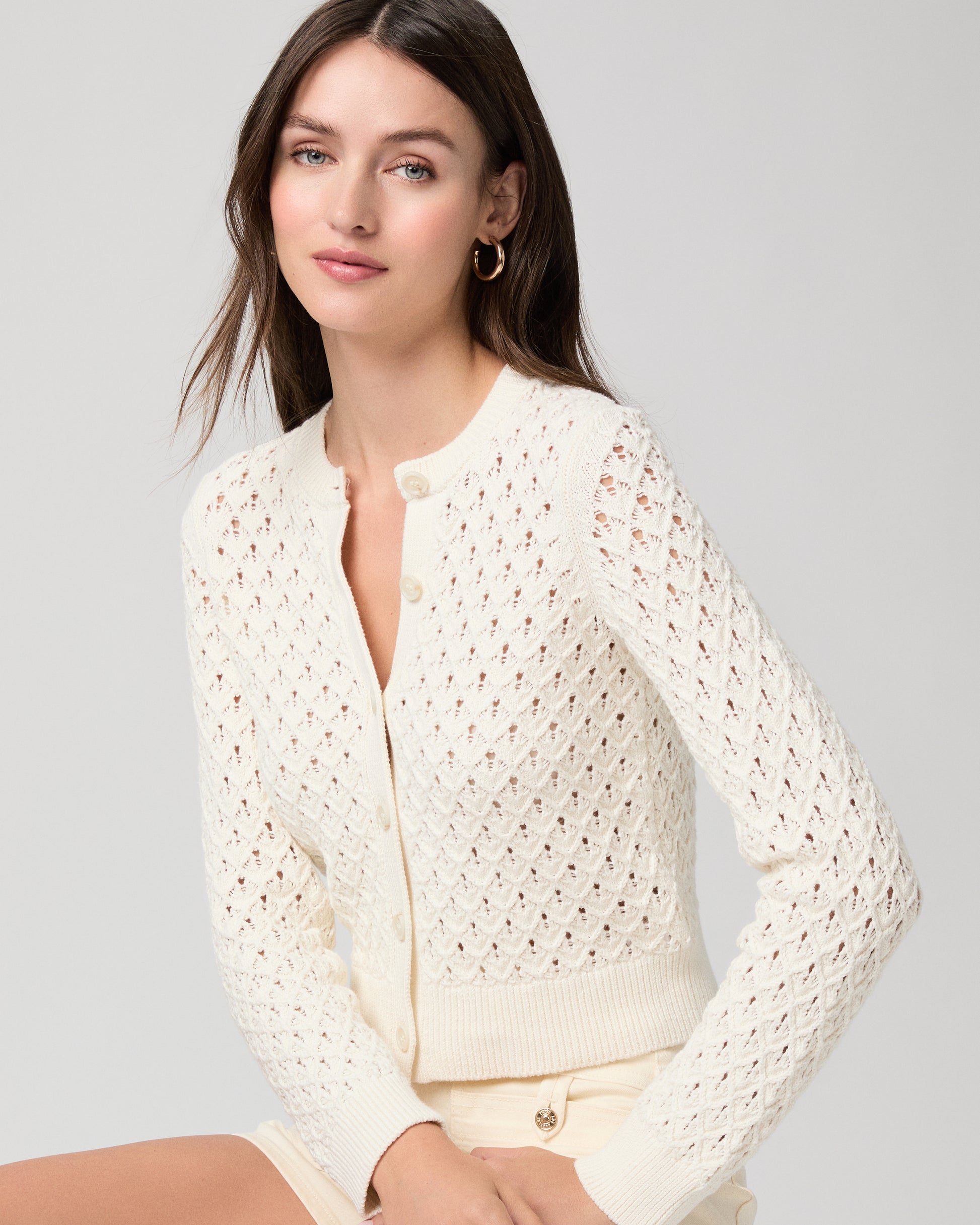 Woman wearing a cream-colored lace top and shorts on a light gray background