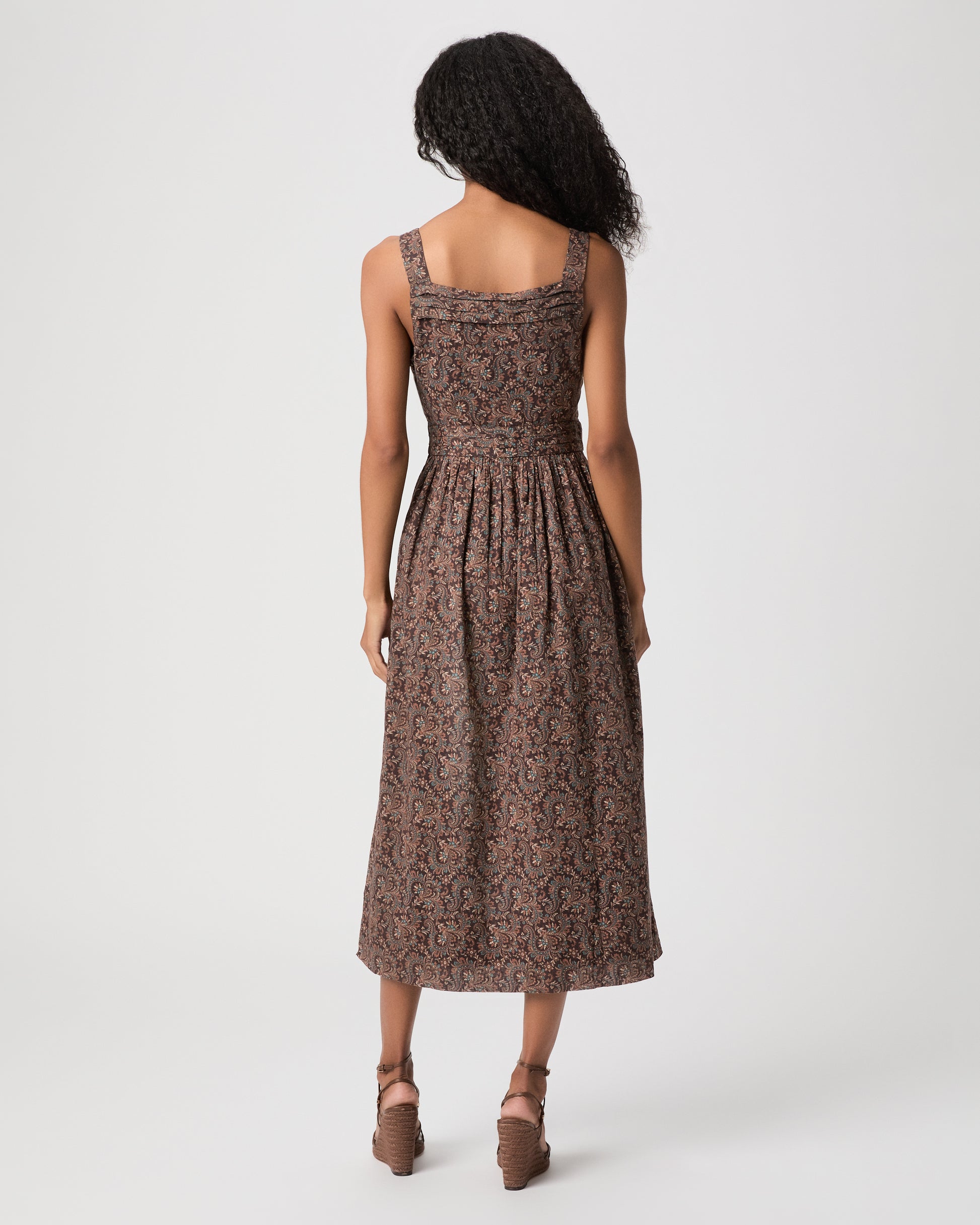 women wearing a brown midi print dress and brown heels against a white background 