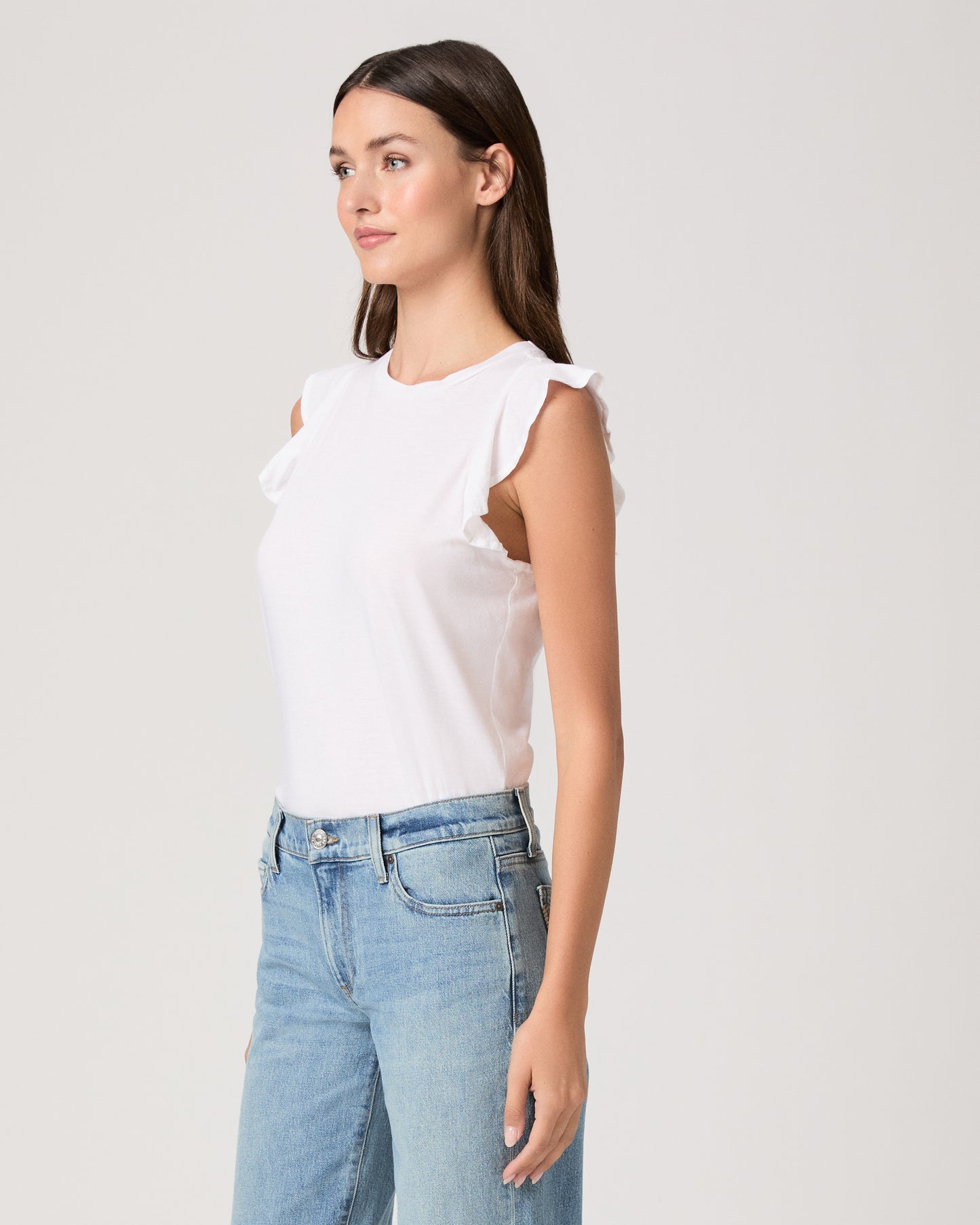 Model wearing a white tee paired with a light wash denim and white sandals