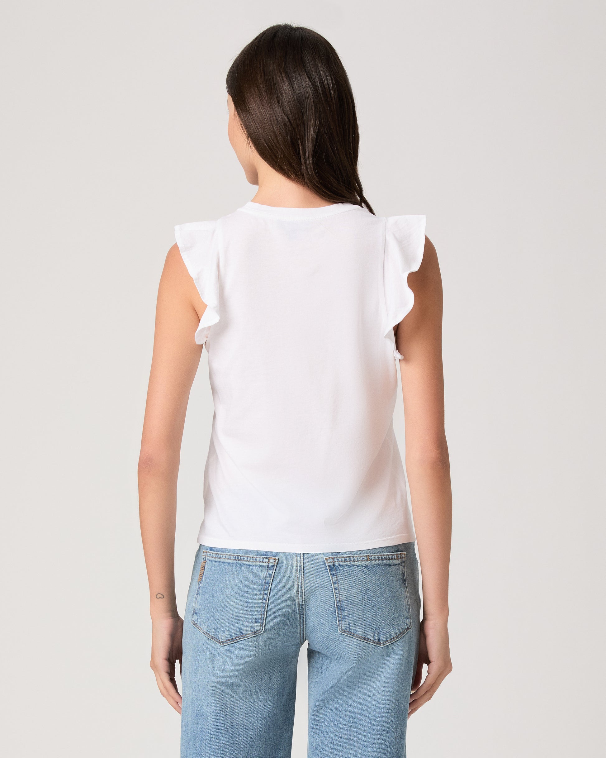 Model wearing a white tee paired with a light wash denim and white sandals