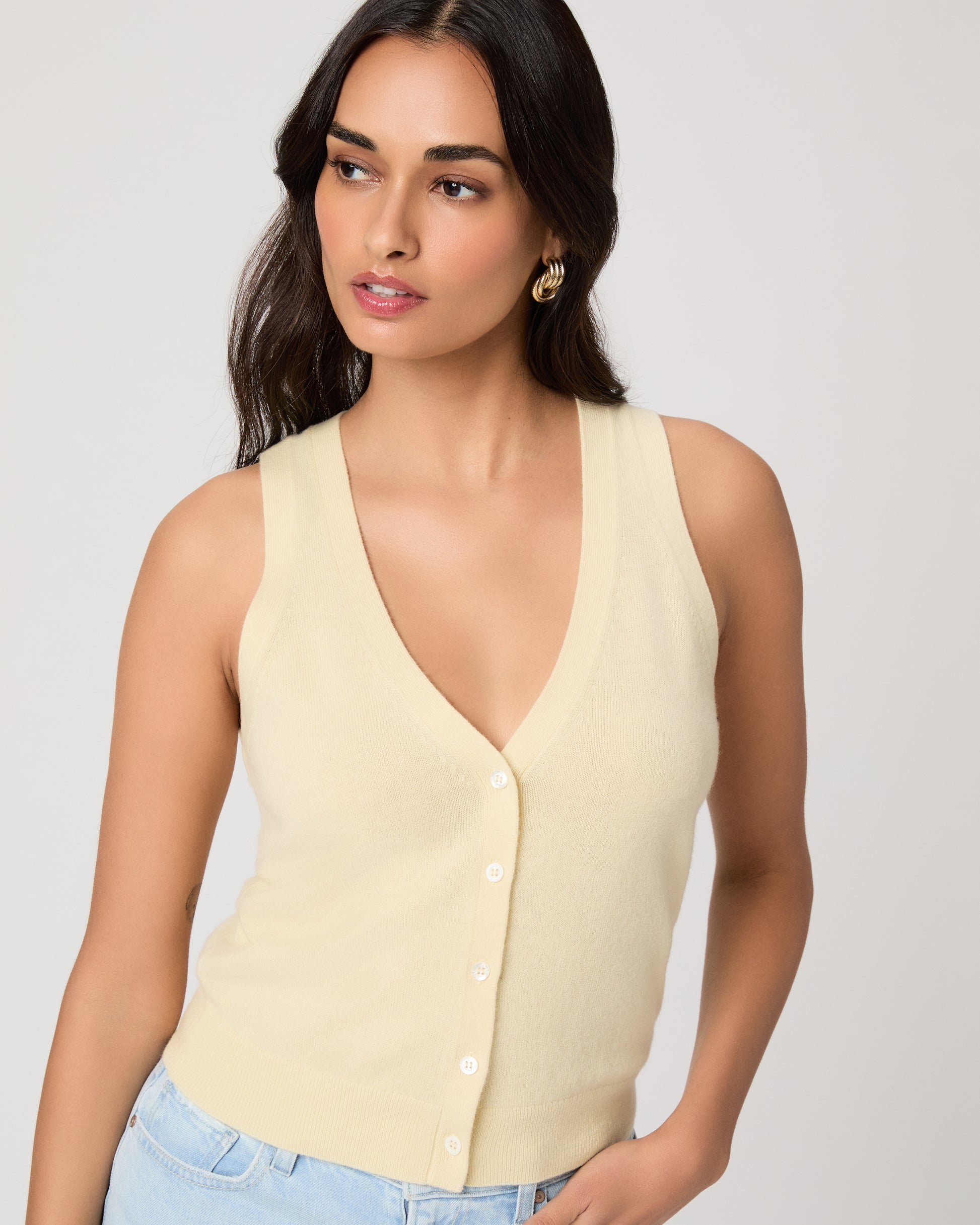 Woman wearing a light yellow sleeveless top against a plain background