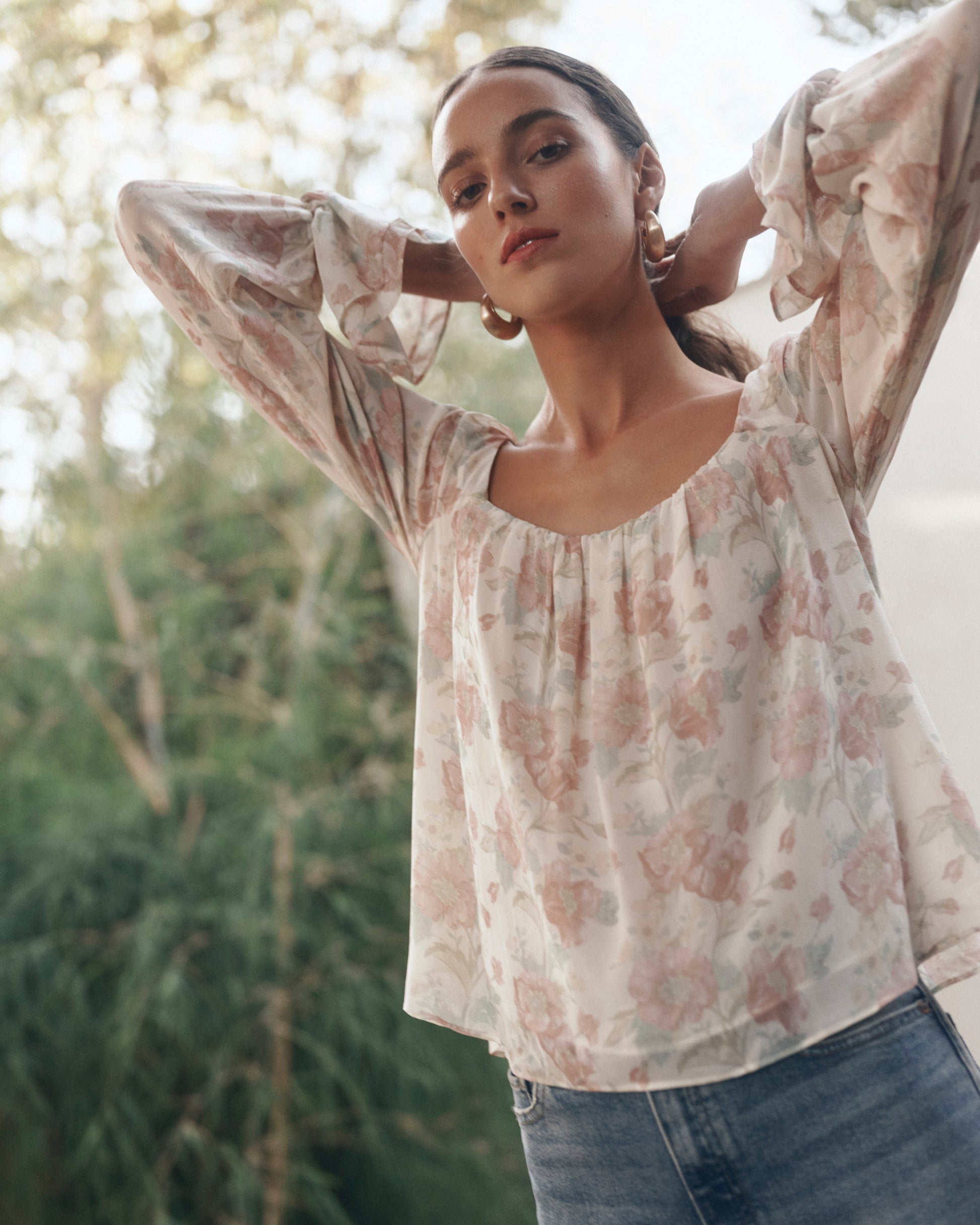 Woman wearing a floral blouse with a blurred natural background