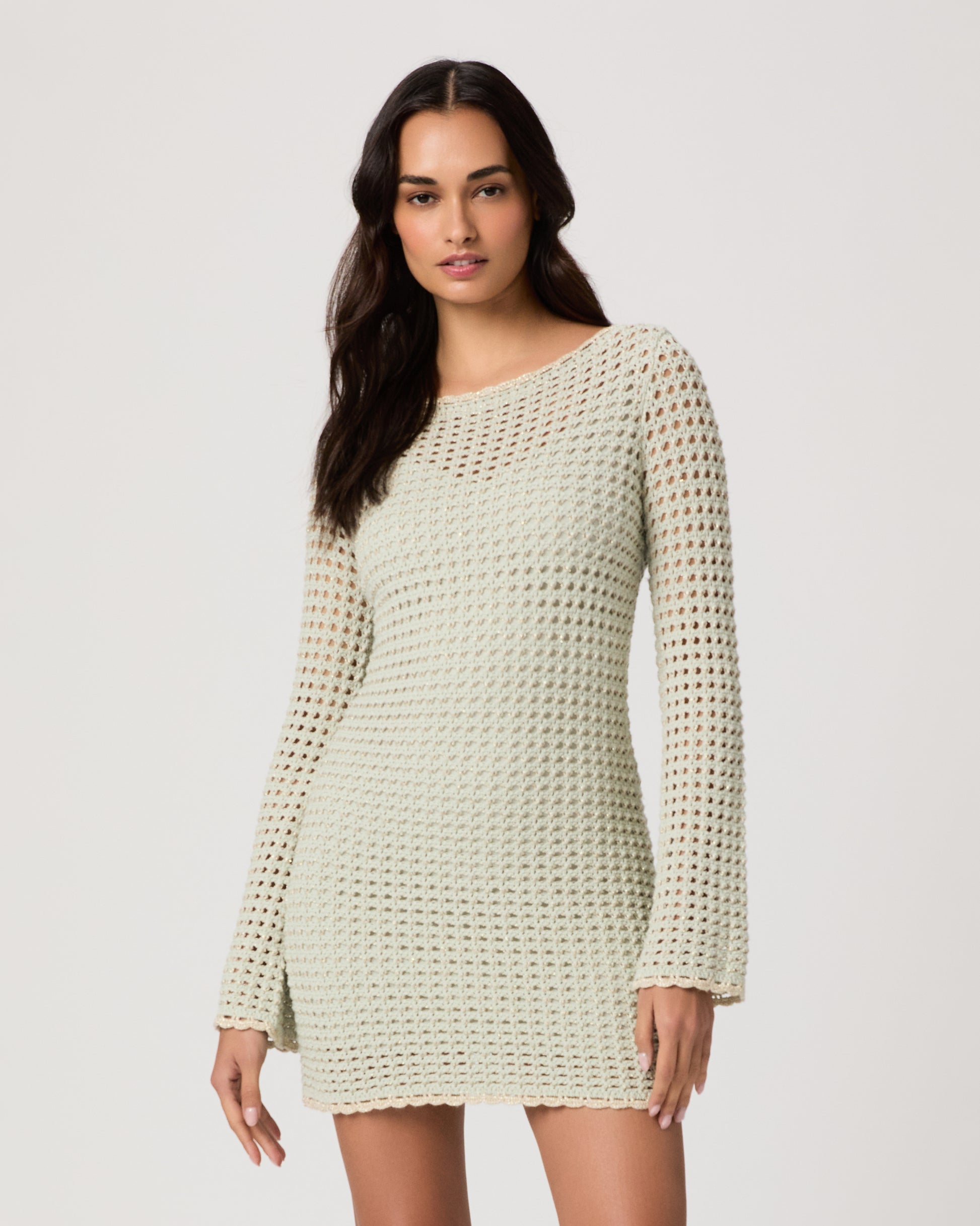 Woman wearing a light green knitted dress on a white background