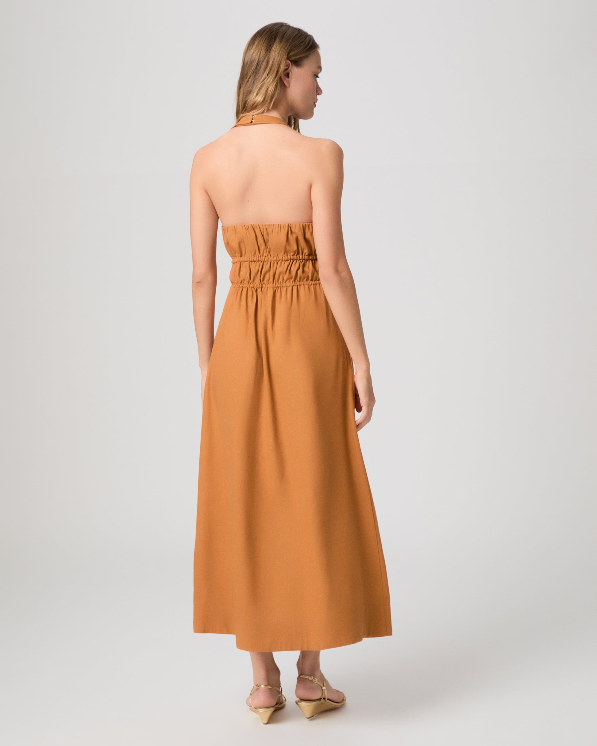 Woman wearing a mustard yellow dress on a white background
