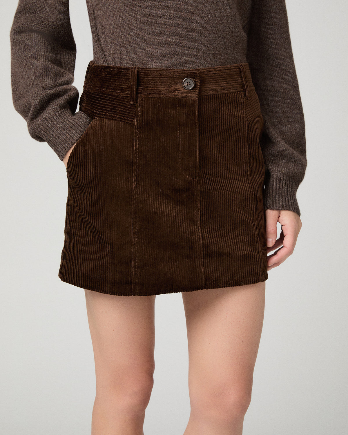 Women wearing a brown sweater and brown skirt against a white background