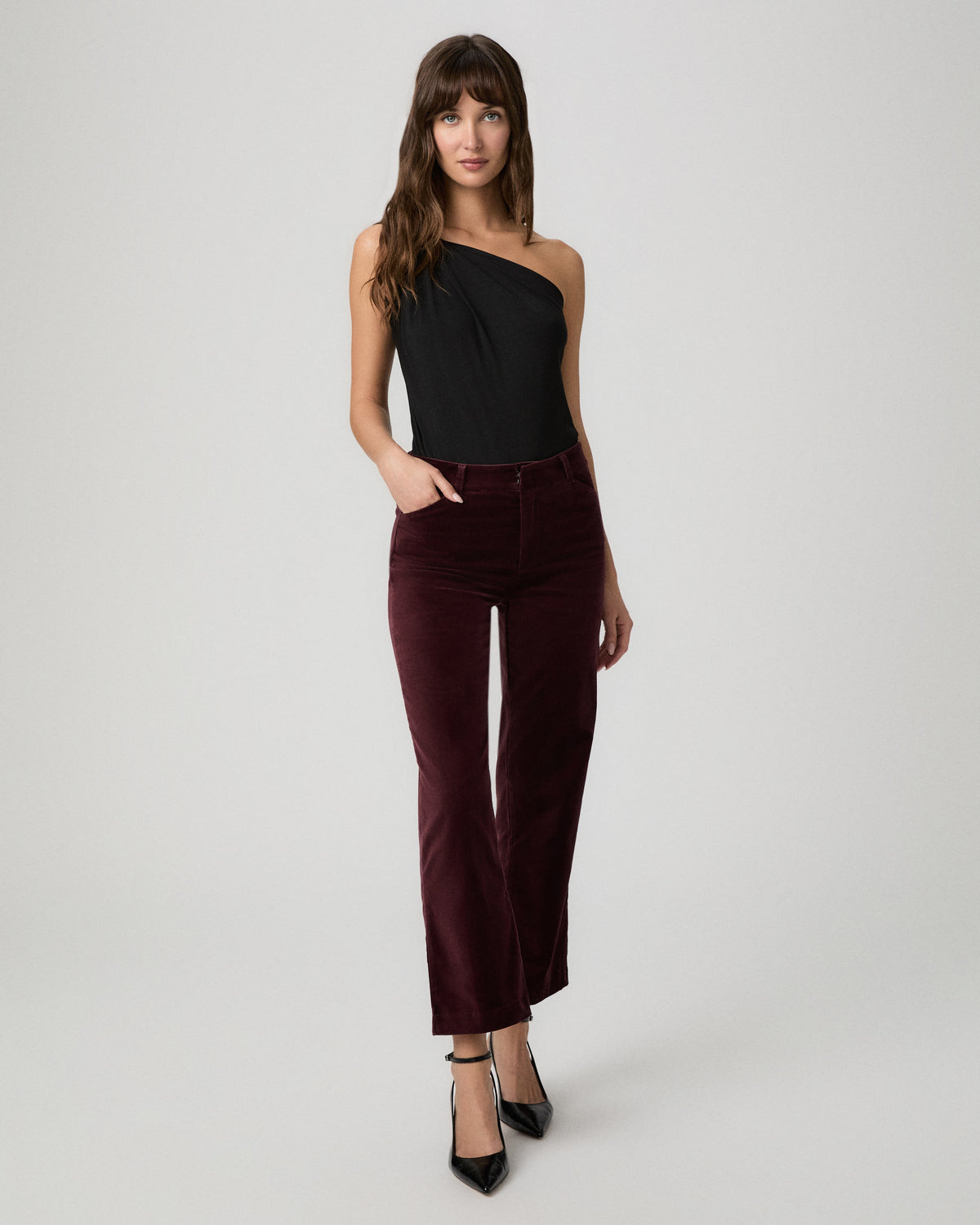 Full-length view of the merlot velvet Stevie Crop Trouser styled with a black one-shoulder top and heels