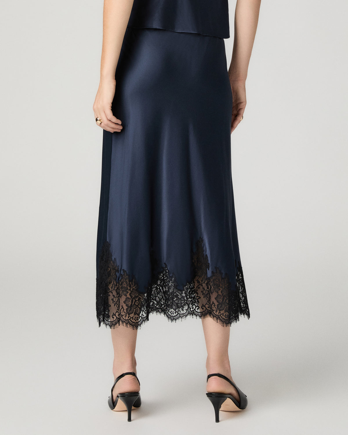 Close-up back view of the navy satin Kelso Skirt, showing the lace hem detail.