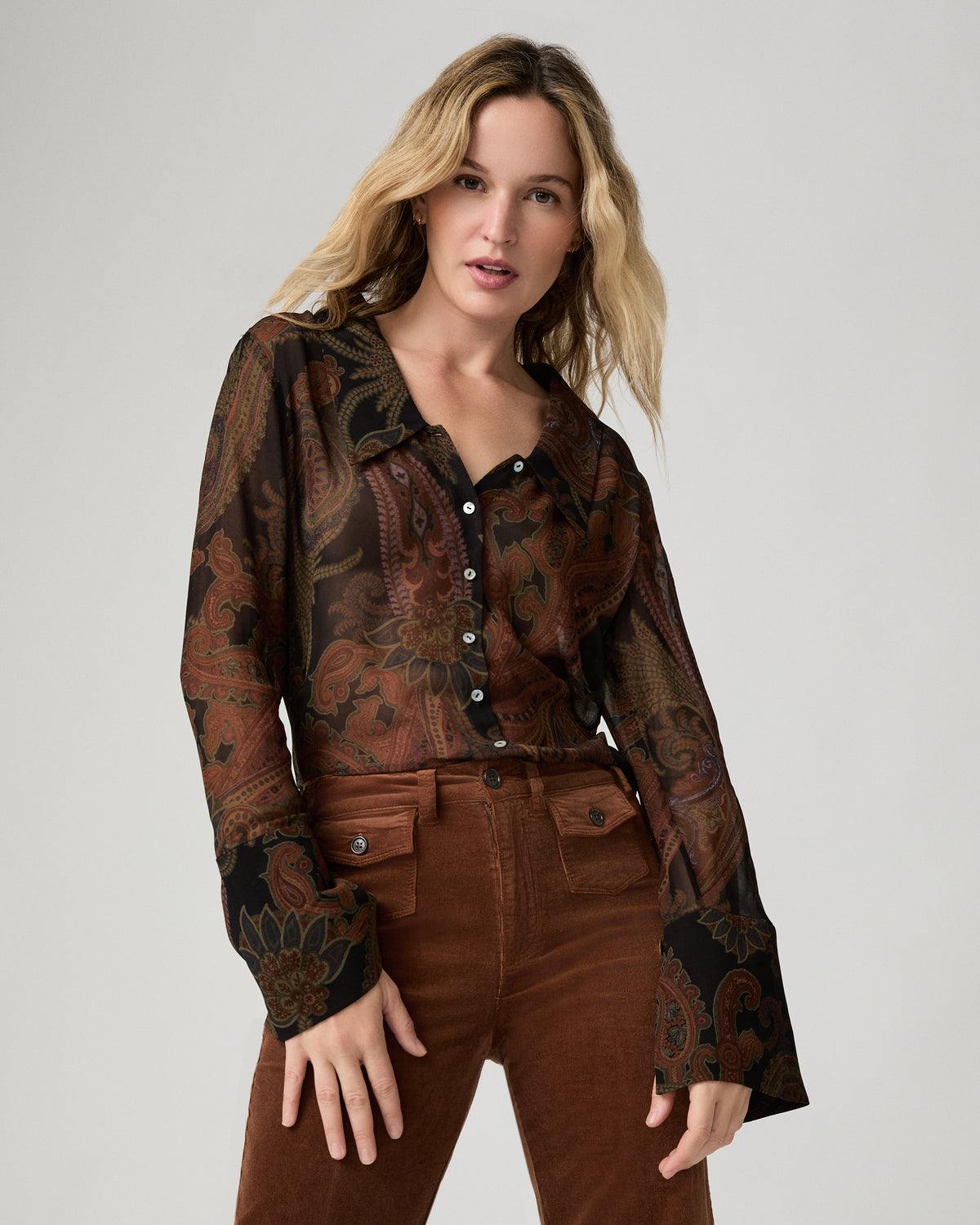 Close-up front view of a woman wearing the black and brown paisley-print Rosalinda Blouse buttoned to the collar.