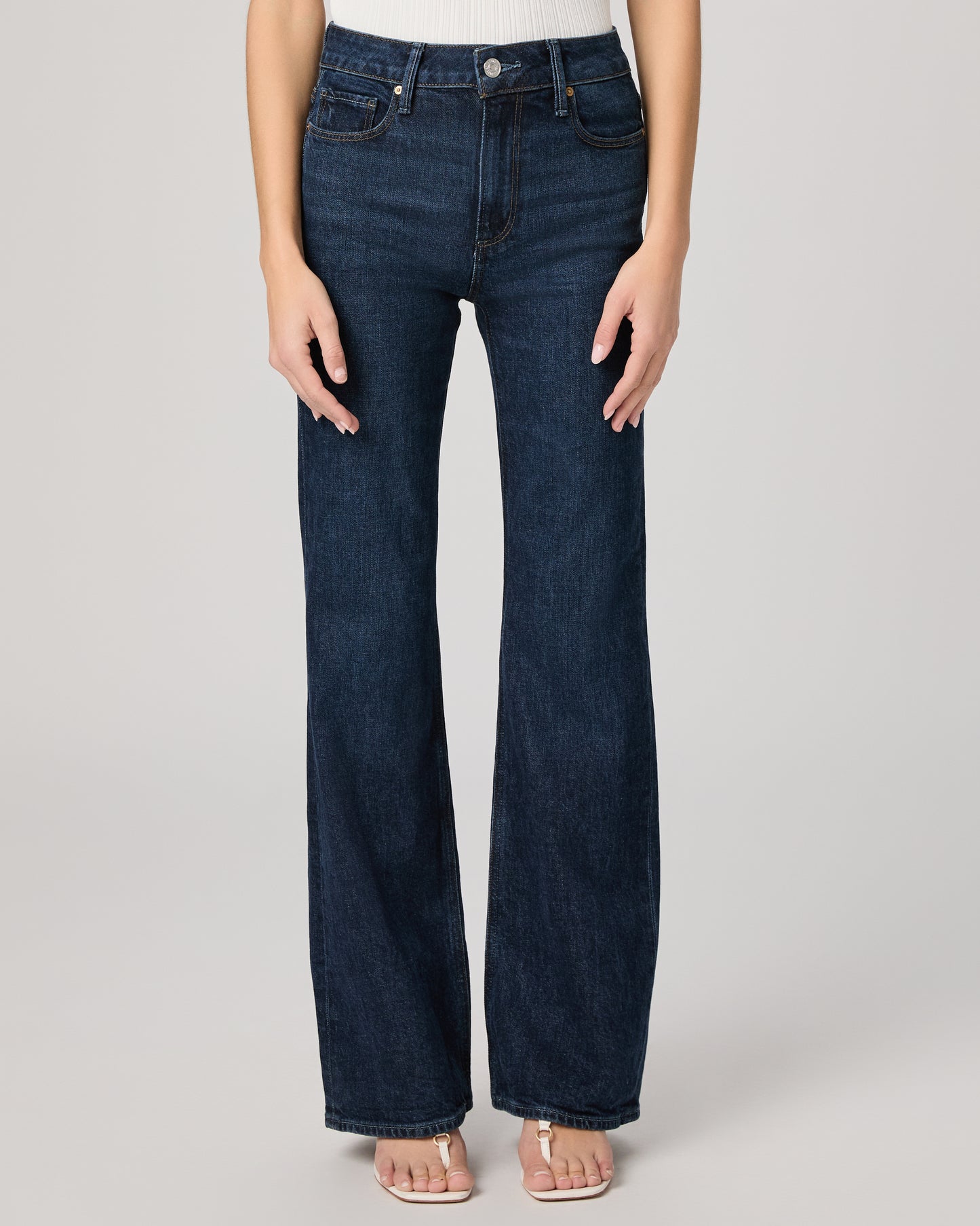 Dark blue jeans worn by a person on a light gray background