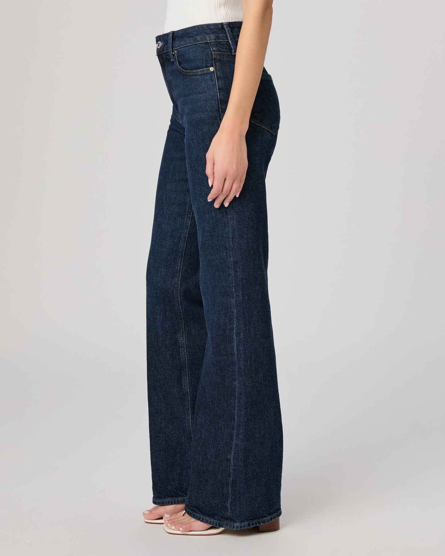 Dark blue jeans worn by a person on a light gray background