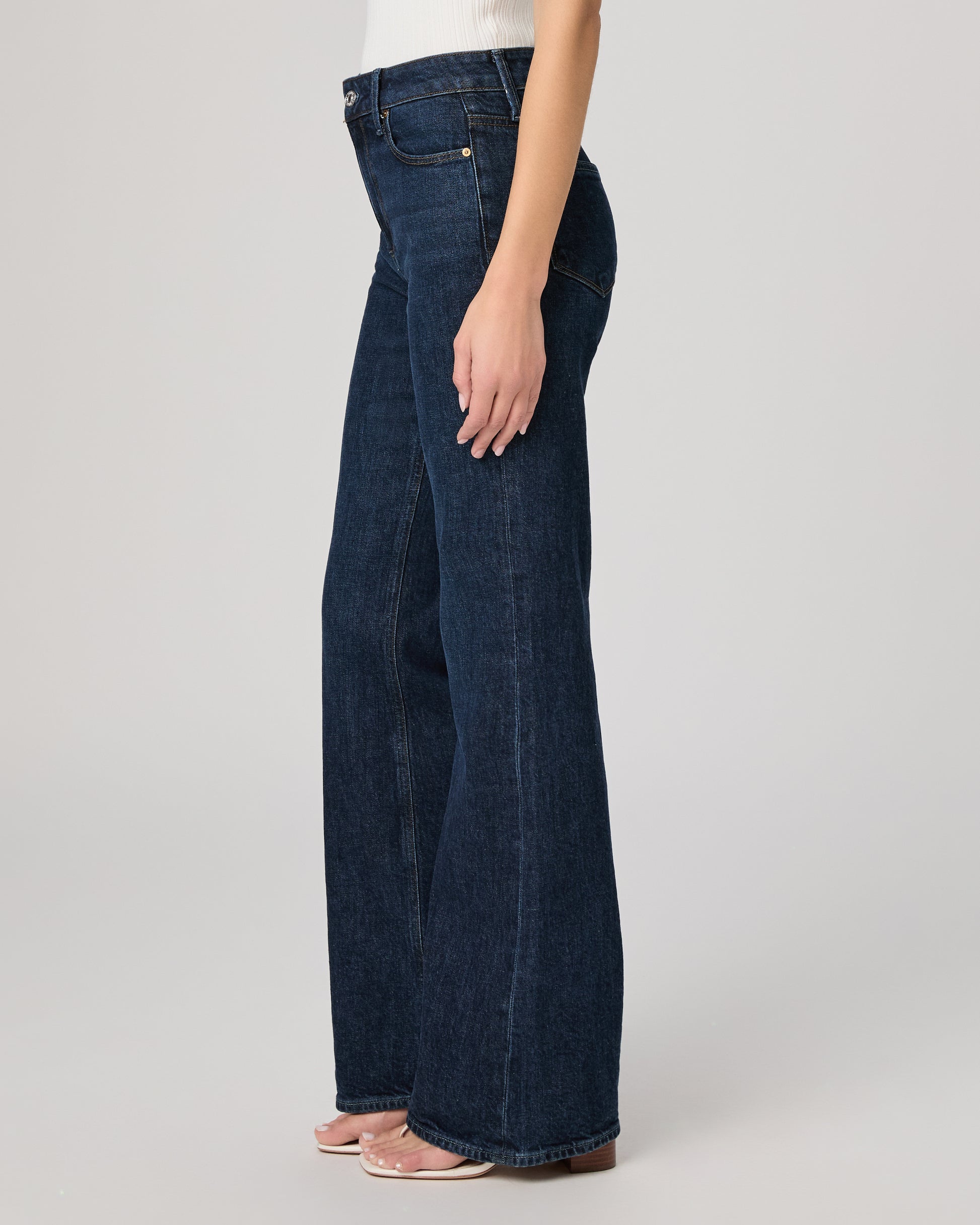 Dark blue jeans worn by a person on a light gray background