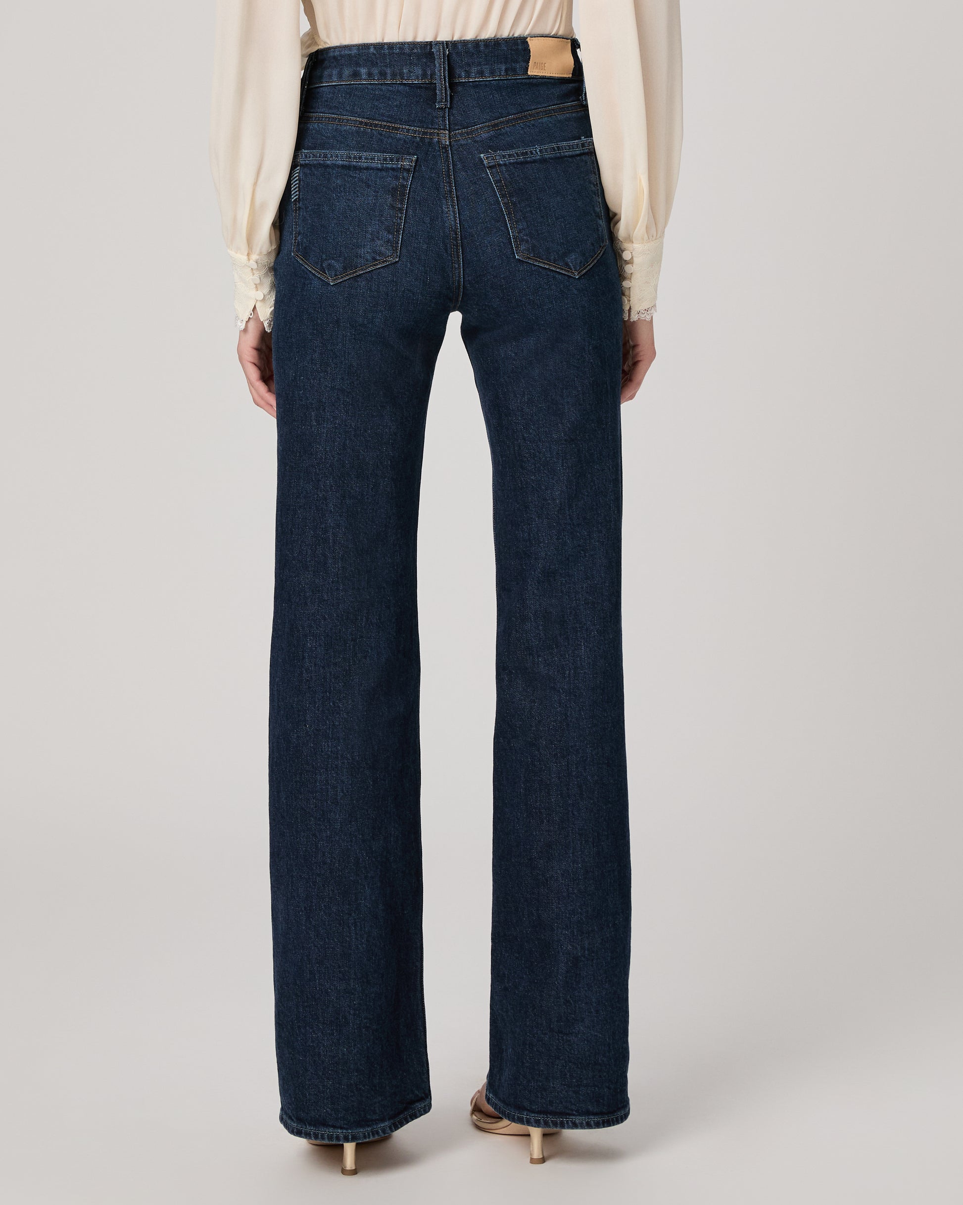 Person wearing dark blue jeans on a plain background