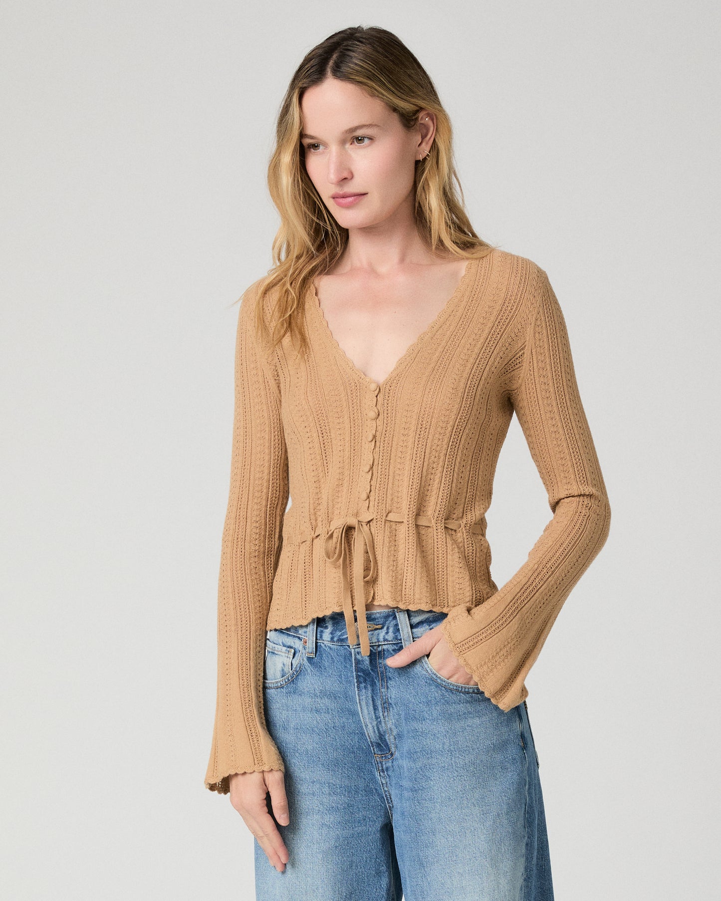 Women wearing a brown top paired with blue jeans against a white background