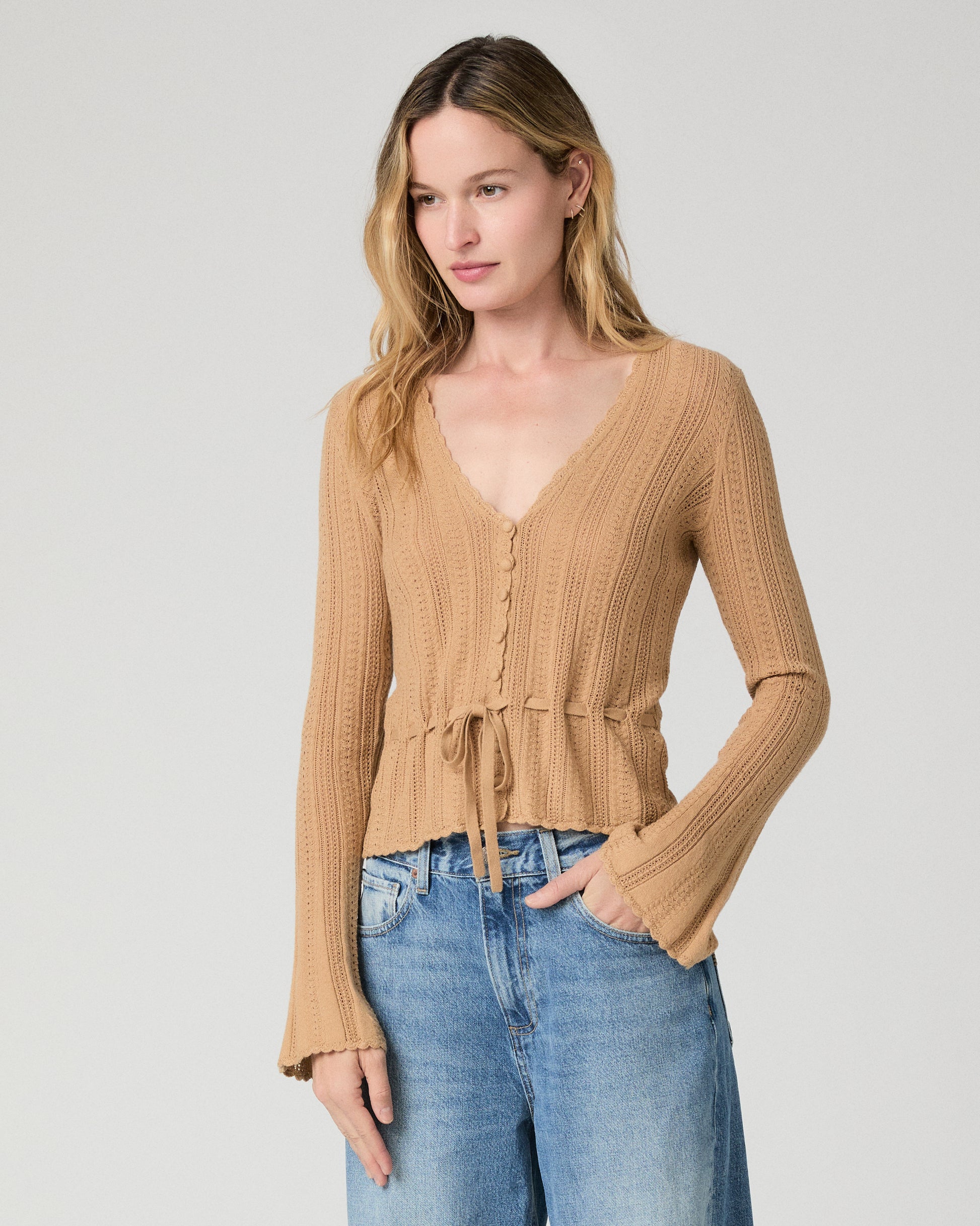 Women wearing a brown top paired with blue jeans against a white background