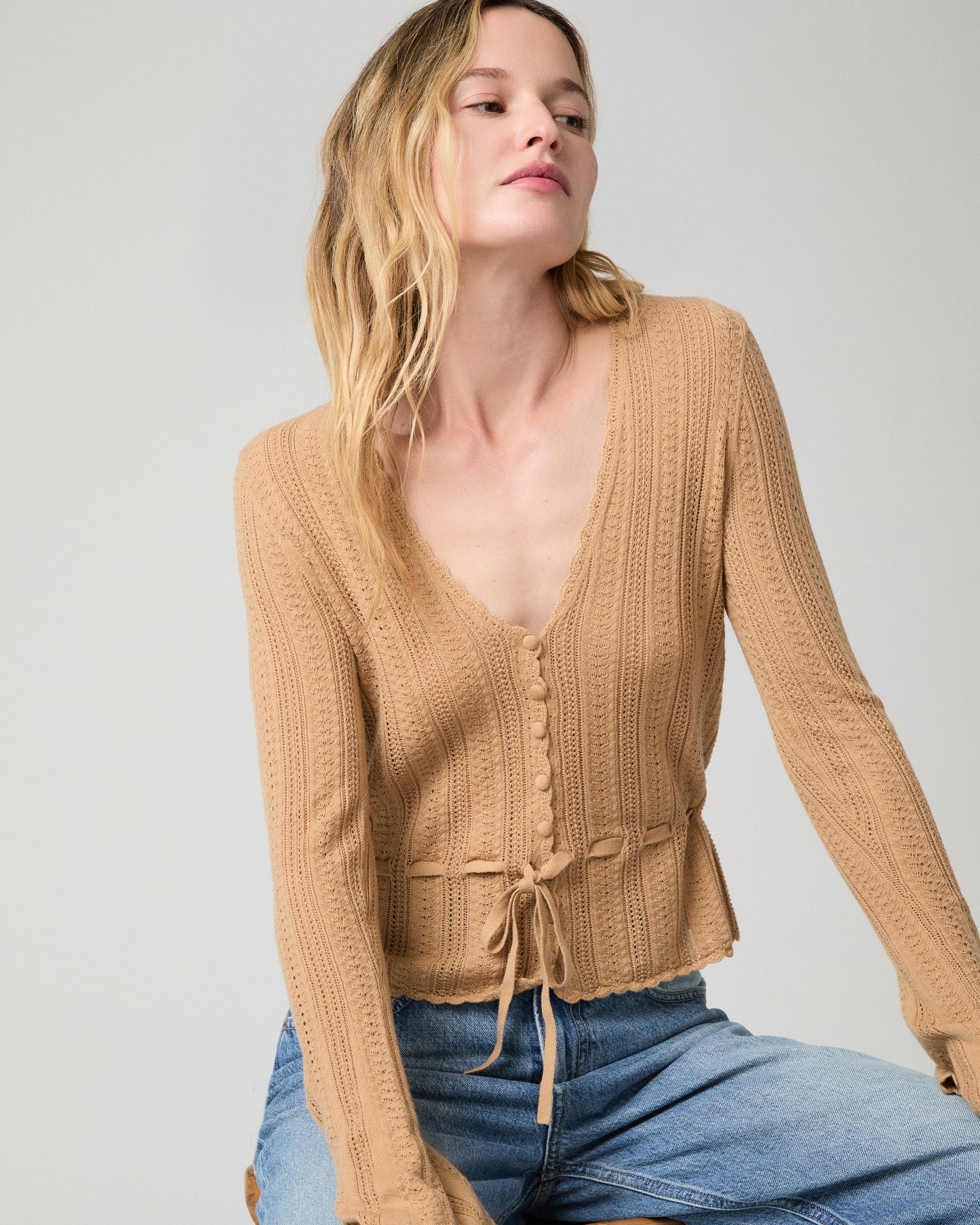 Women wearing a brown top paired with blue jeans against a white background