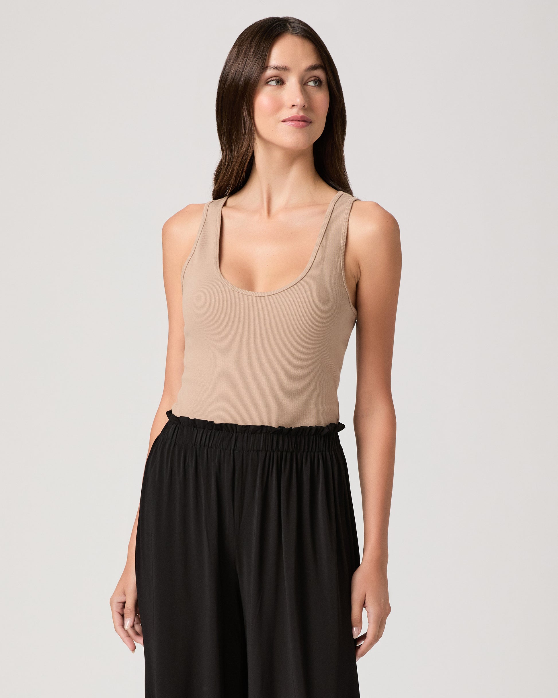 Model wearing a beige tank top paired with black pants 