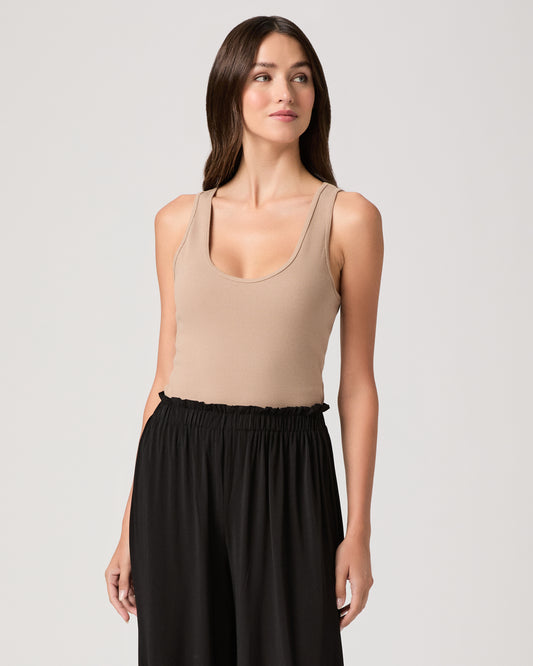 Model wearing a beige tank top paired with black pants 