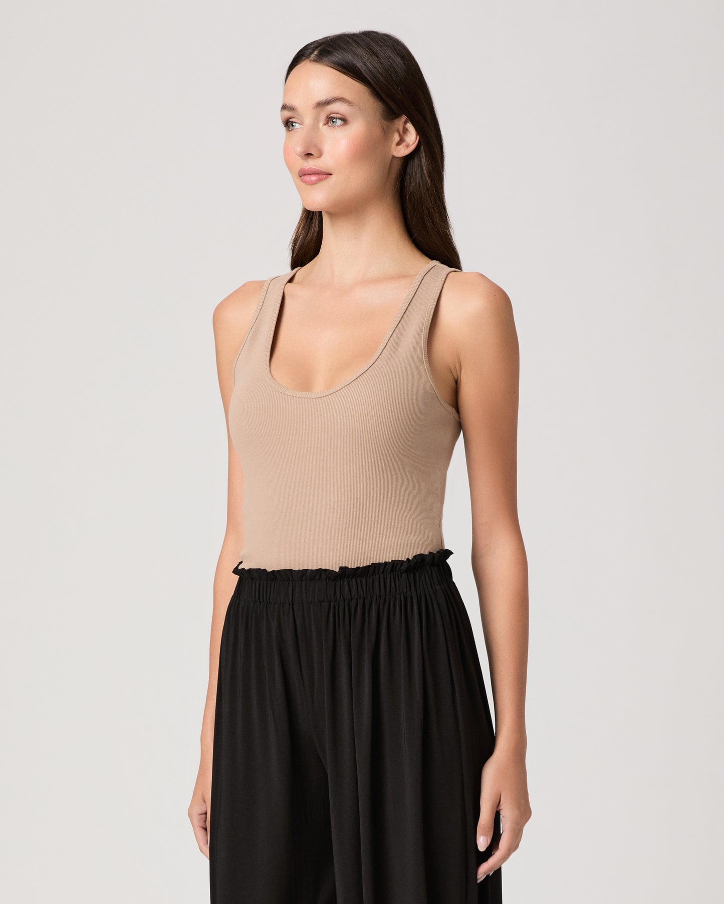Model wearing a beige tank top paired with black pants