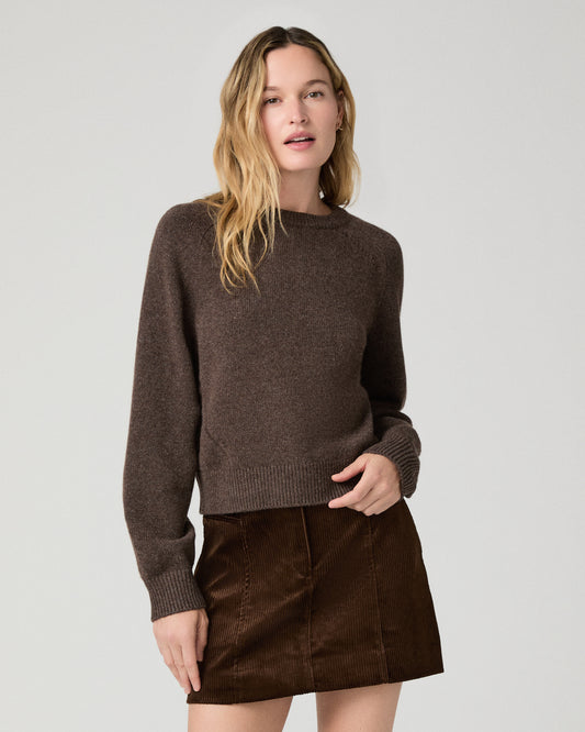 Women wearing a brown long sleeve sweater paired with a brown skirt against a white background