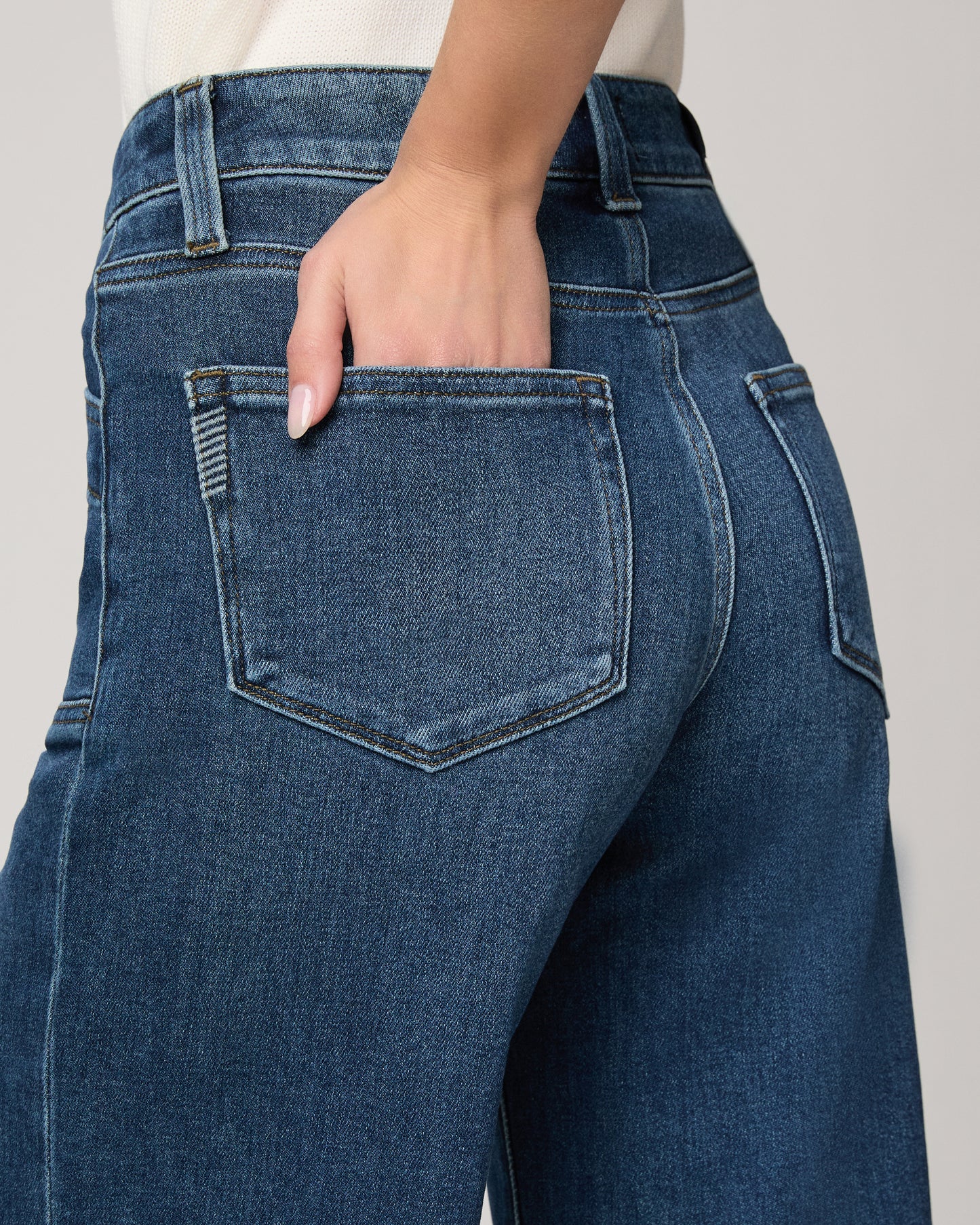 Woman wearing a white blouse and blue jeans on a plain background
