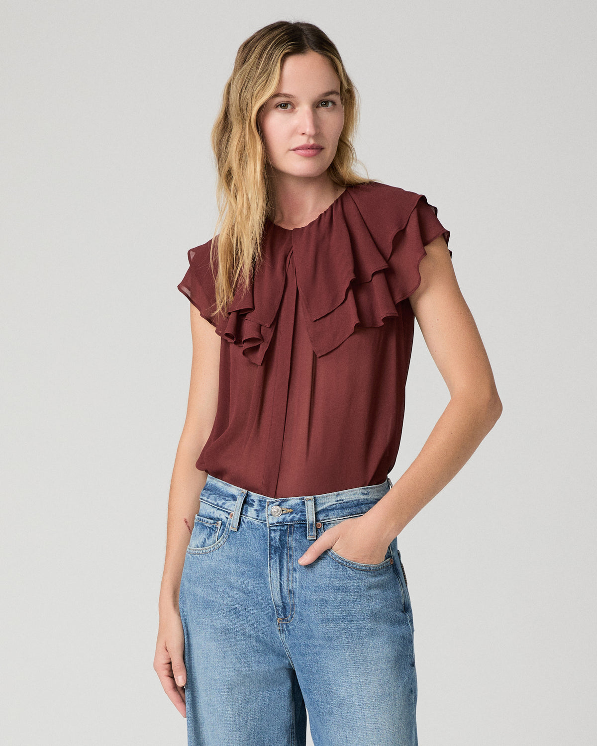 Women wearing red blouse  and blue jeans against a white background