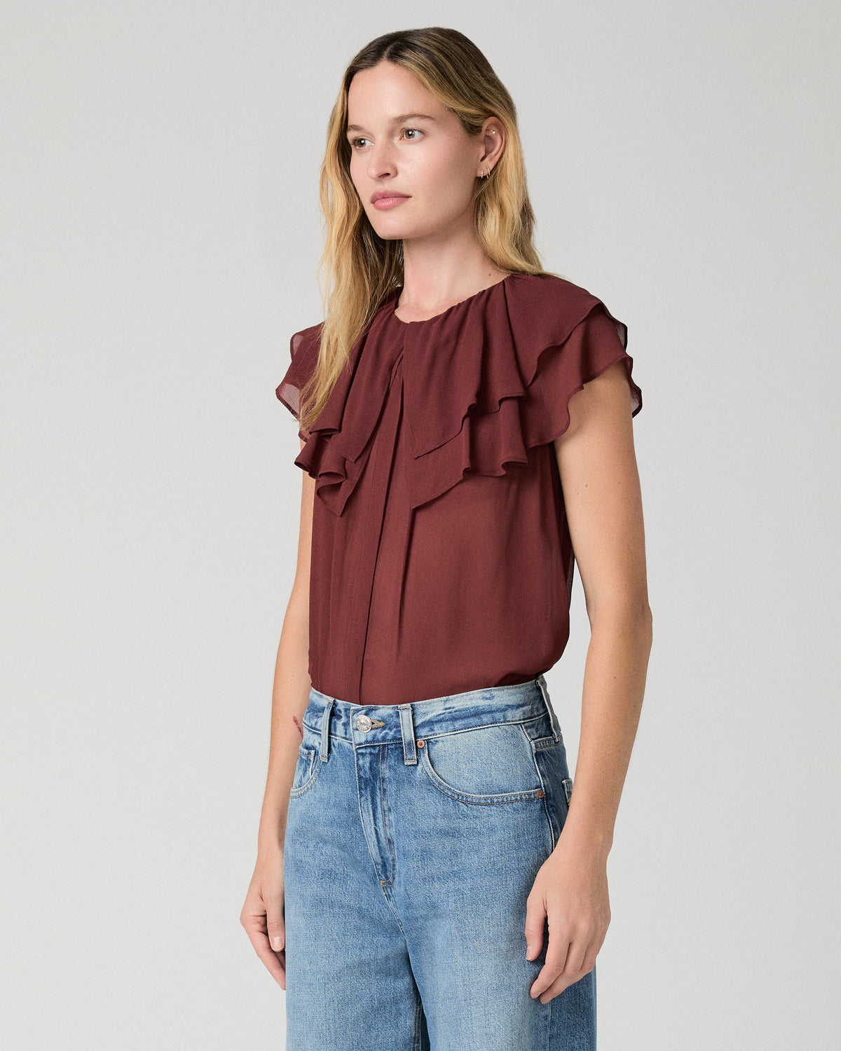 Women wearing red blouse and blue jeans against a white background