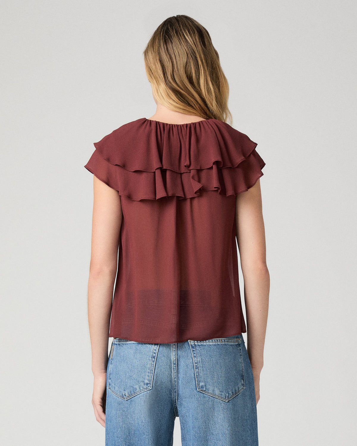 Women wearing red blouse  and blue jeans against a white background