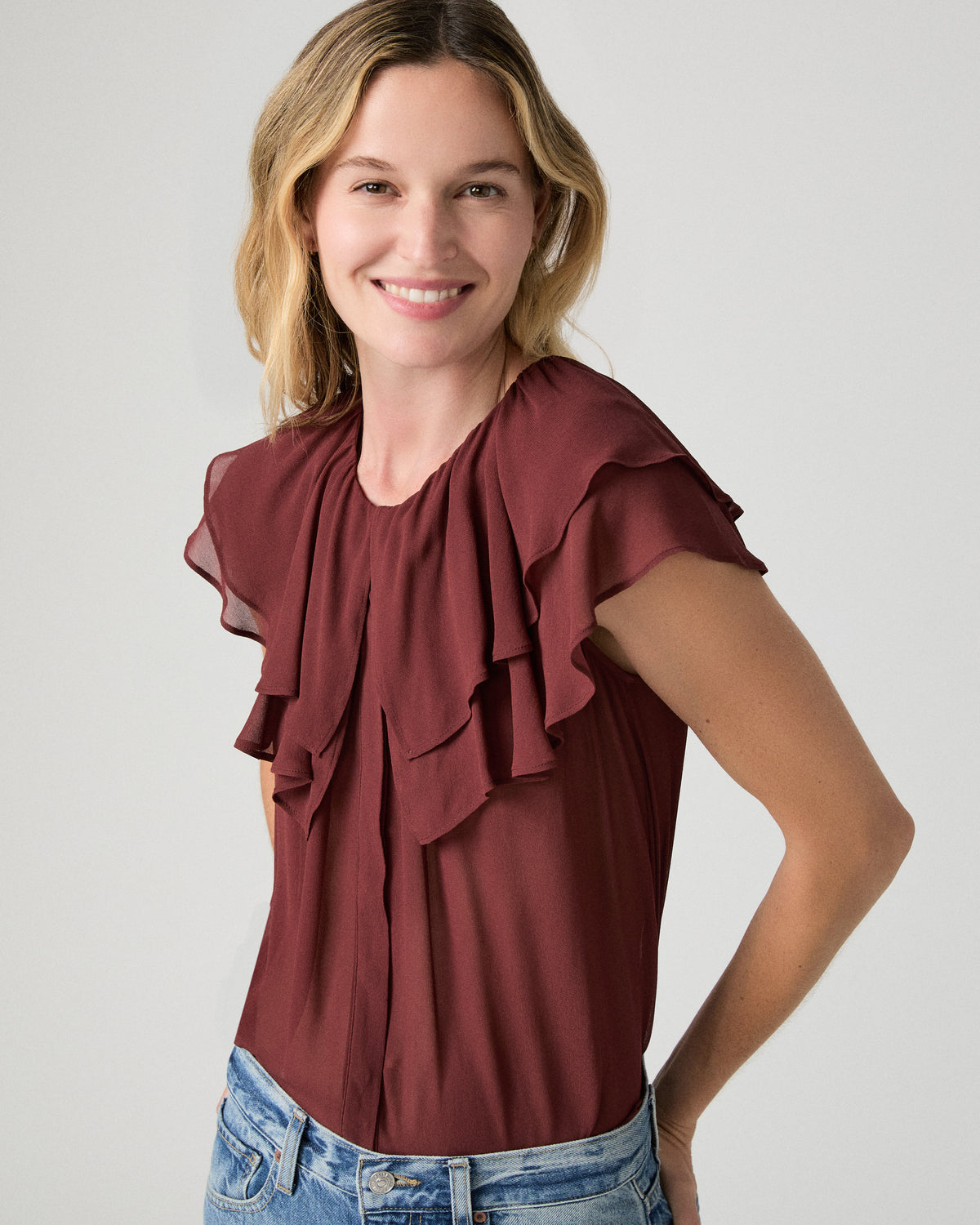 Women wearing red blouse  and blue jeans against a white background