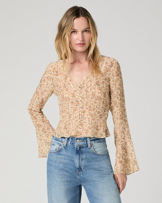 Women wearing a flower printed brown blouse and blue jeans against a white background
