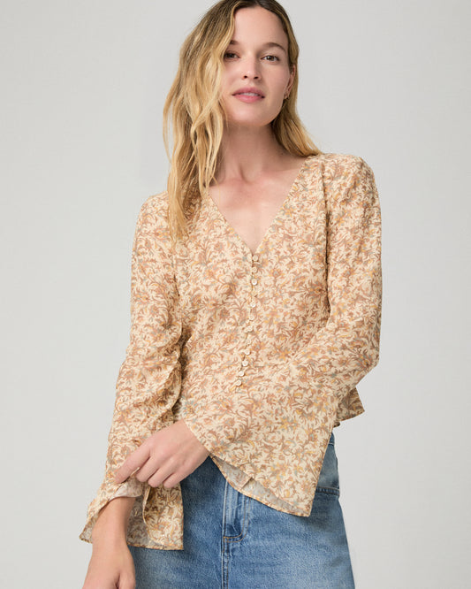 Women wearing a flower printed brown blouse and blue jeans against a white background
