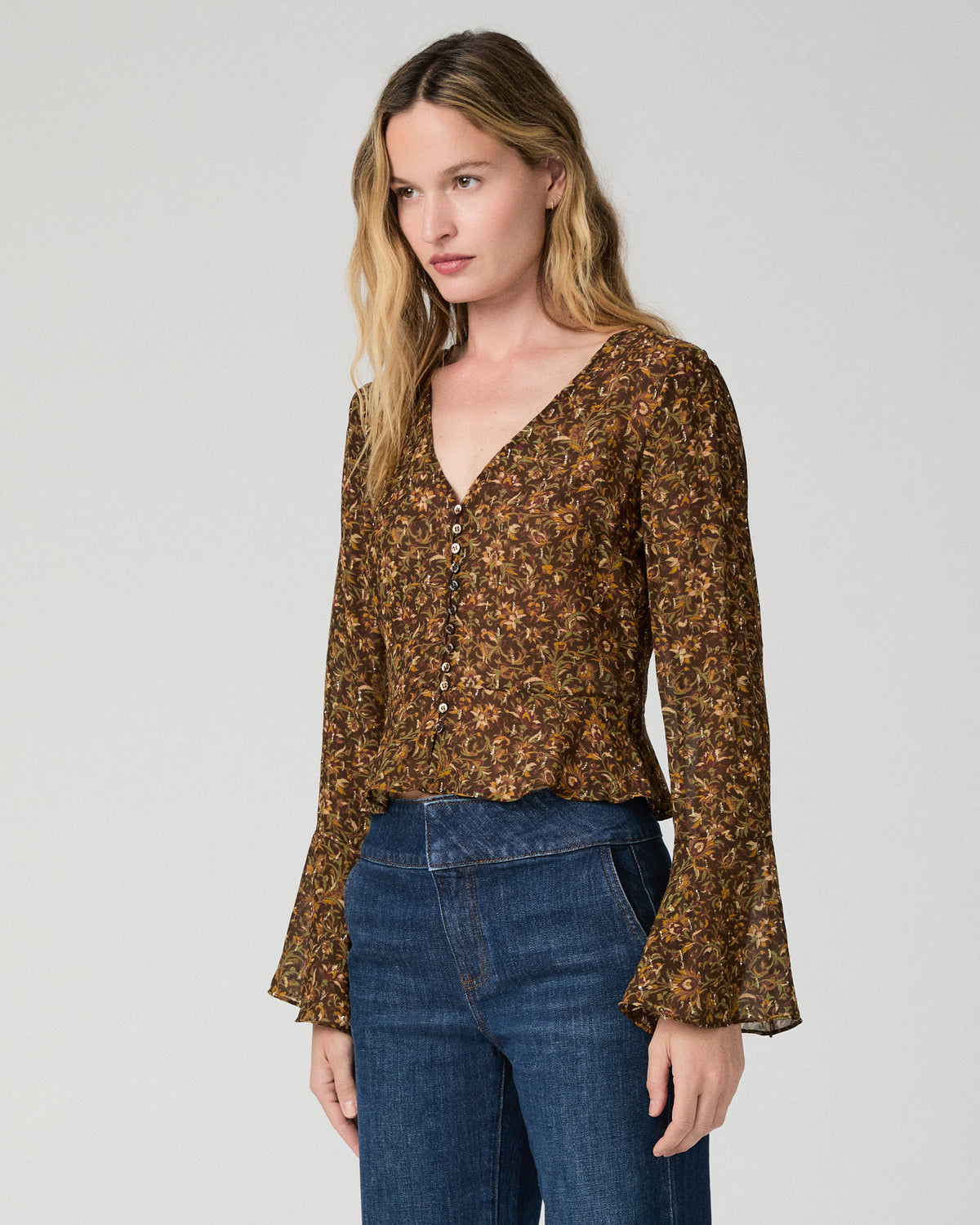 Women wearing a flower print blouse paired with blue jeans against a white background