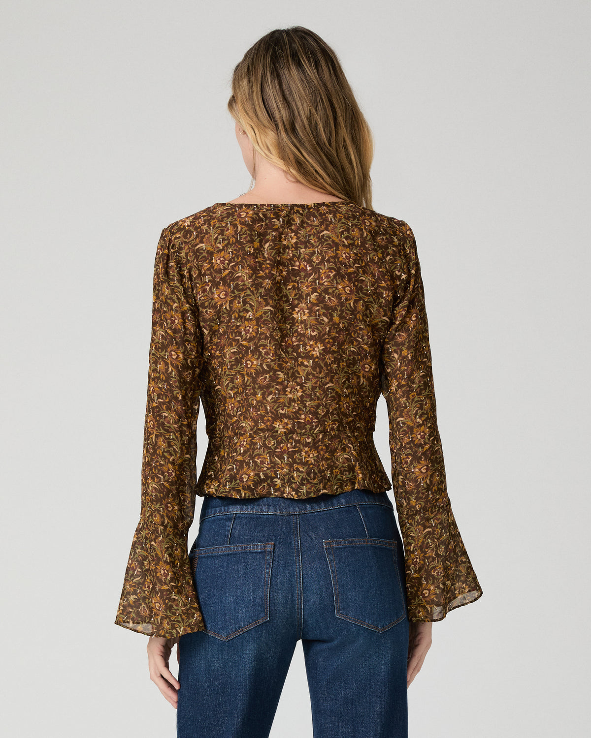 Women wearing a flower print blouse paired with blue jeans against a white background