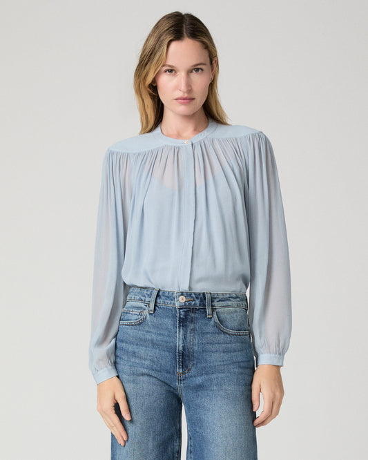 Women wearing a light blue blouse and blue jeans against a white background